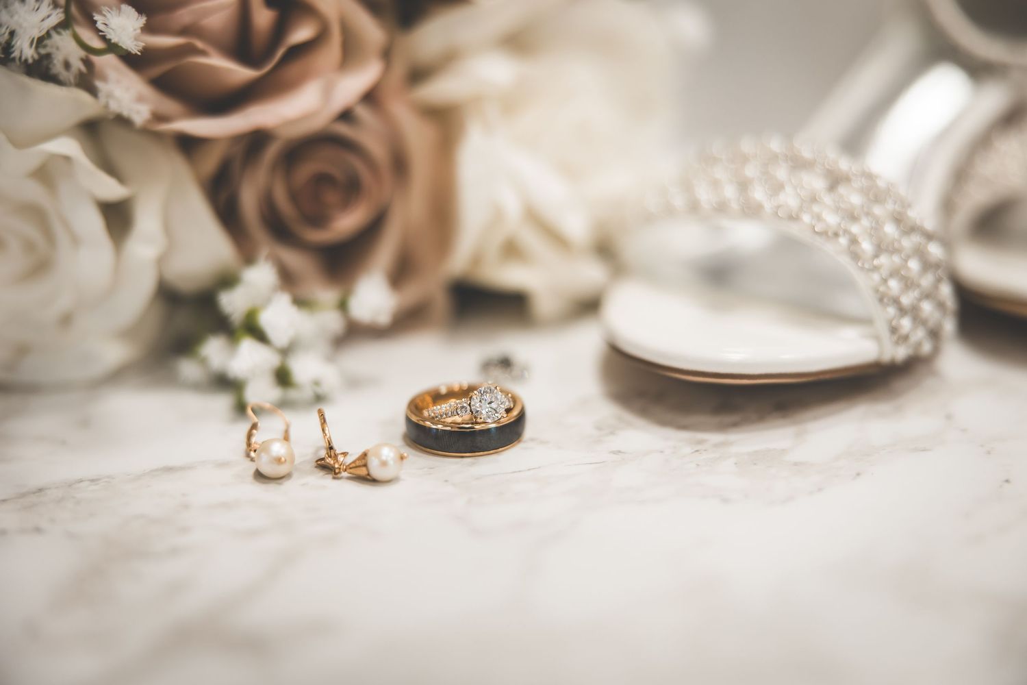 Wedding rings and delicate jewelry details arranged on a neutral surface.
