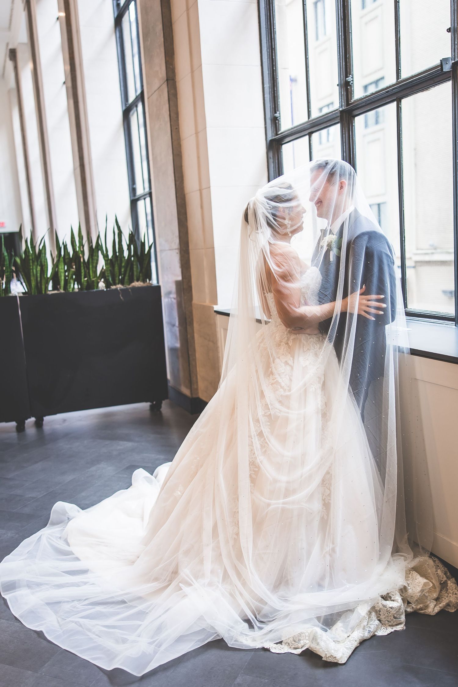 Ethereal bridal veil flowing around a couple during an intimate wedding moment.