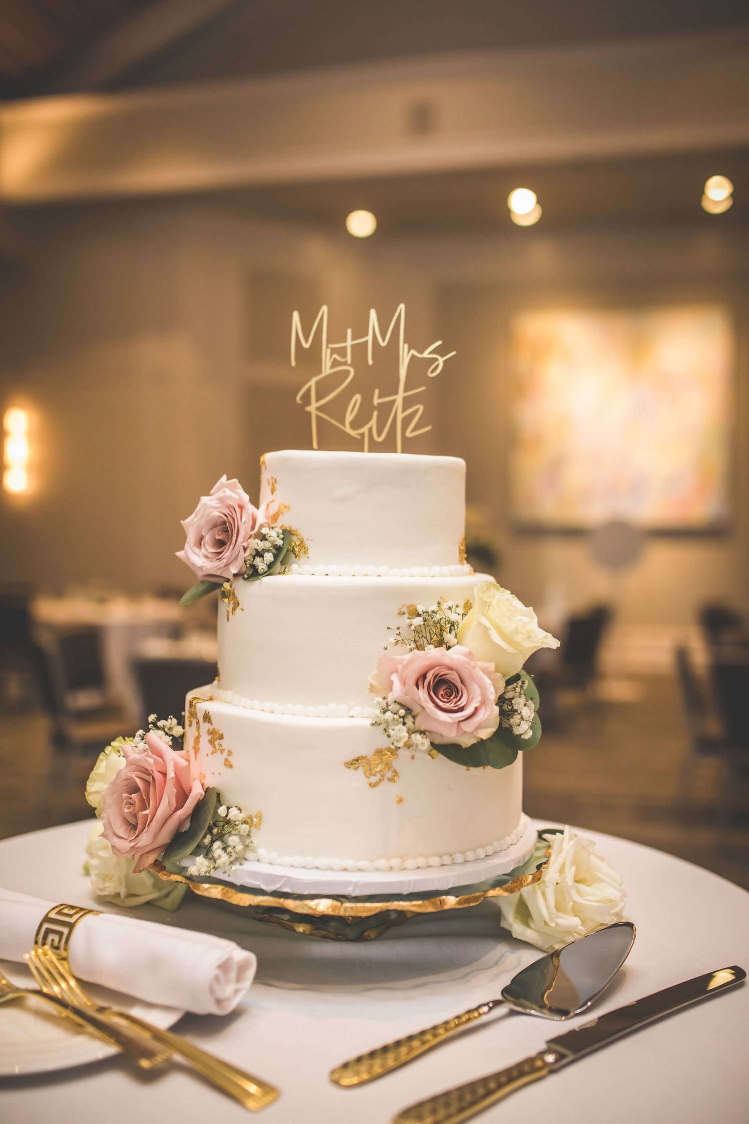 Elegant white wedding cake adorned with dusty pink roses and delicate floral decorations.