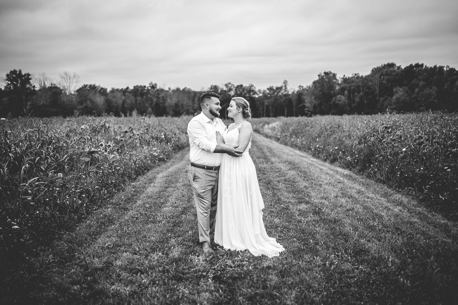 Black and white photo of couple walking through a countryside field.