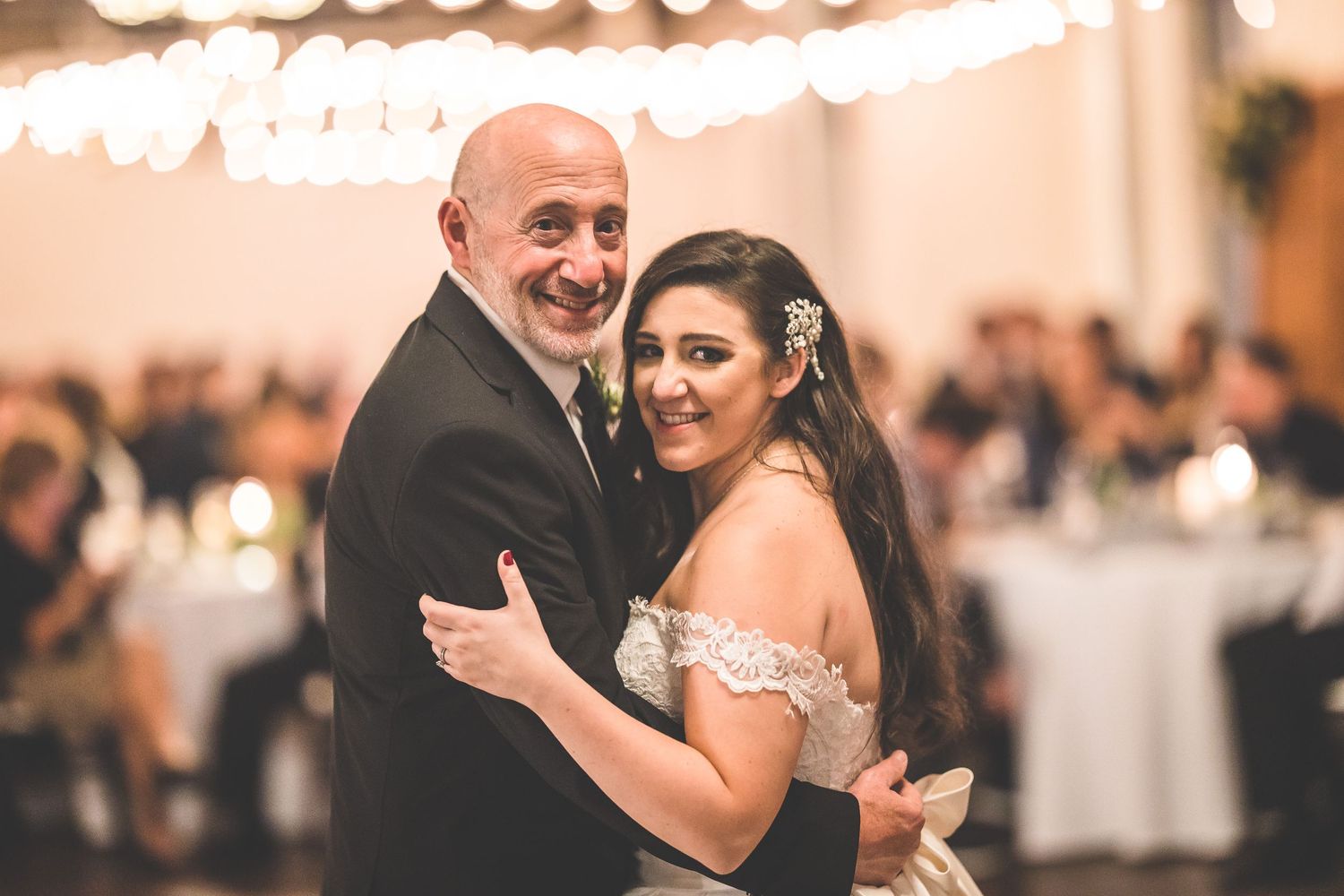 Intimate dance moment shared between couple during wedding reception under warm lighting.