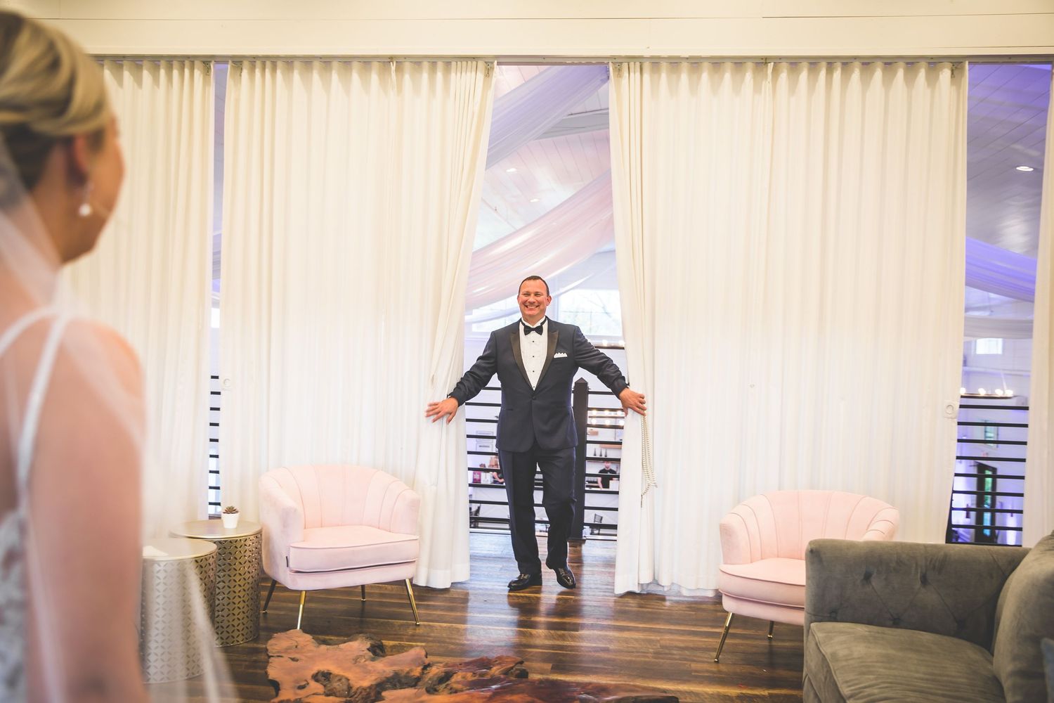 First look moment captured in an elegant indoor venue with white curtains.