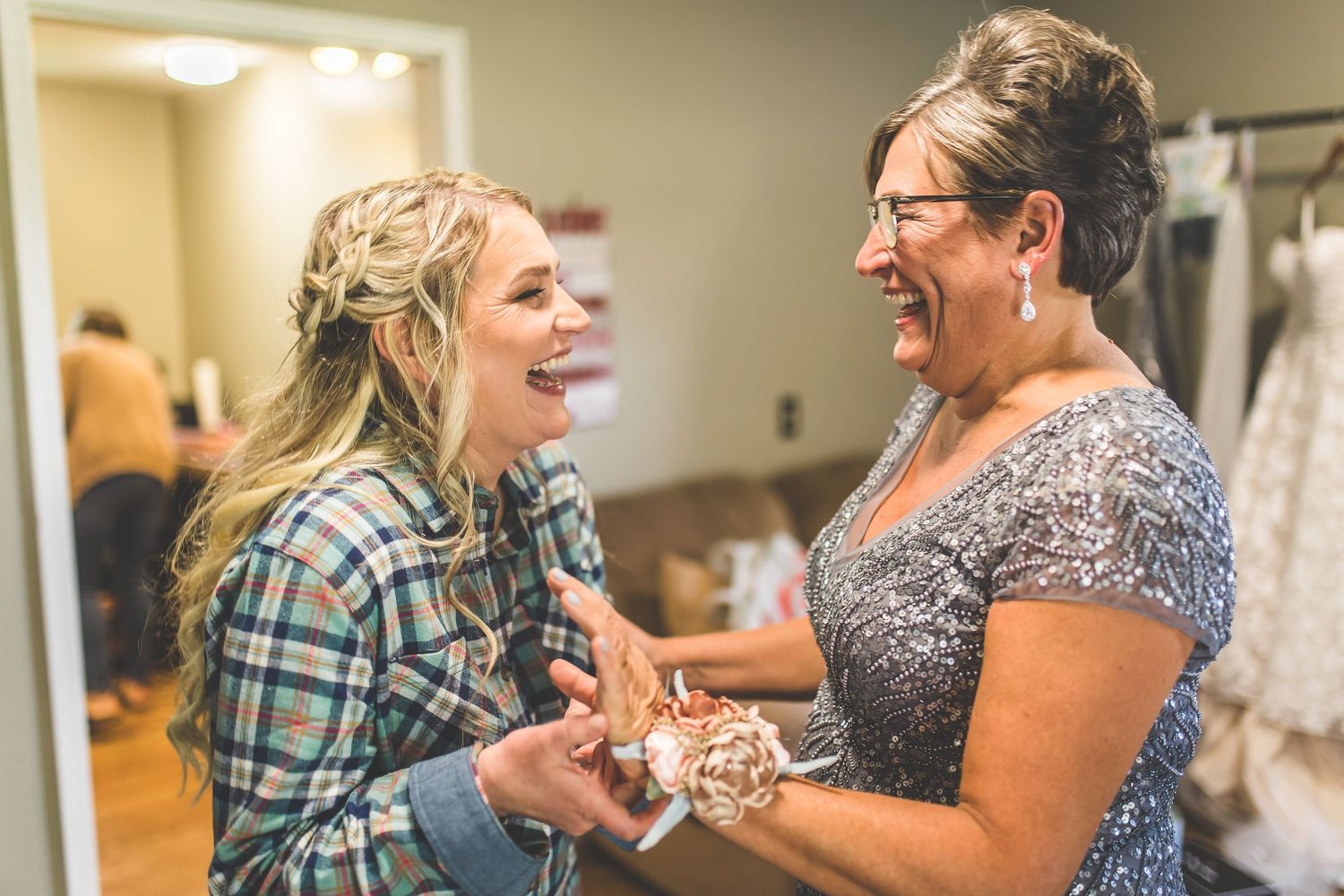Group of people sharing joyful moments during wedding preparations in a brightly lit room.