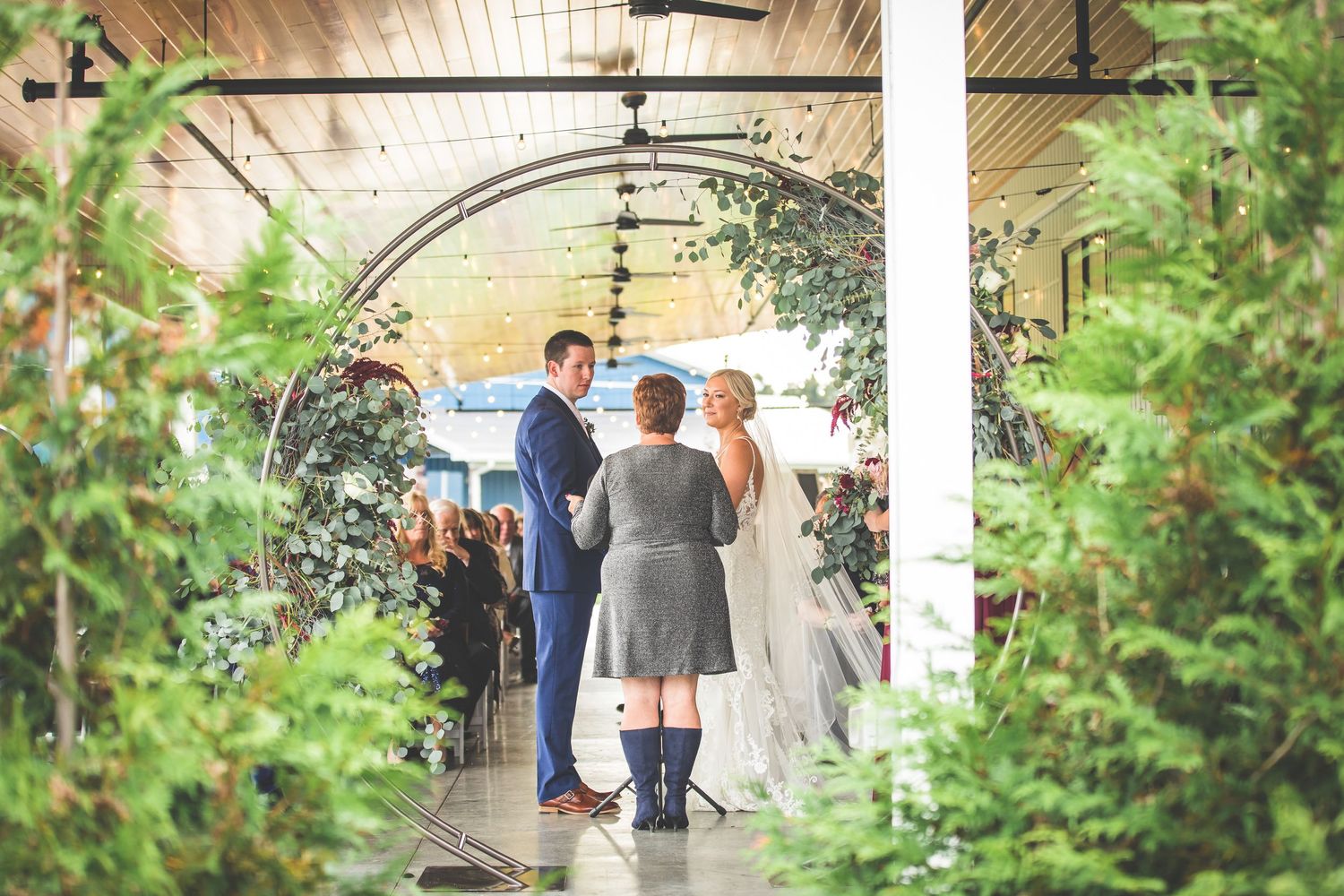 Wedding ceremony space decorated with natural greenery and white floral arrangements.