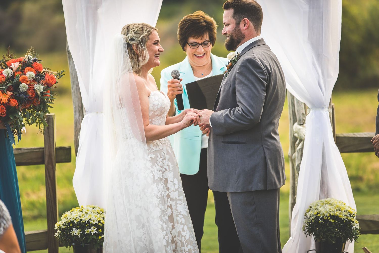 Intimate wedding ceremony moment under white canopy with orange floral accents.