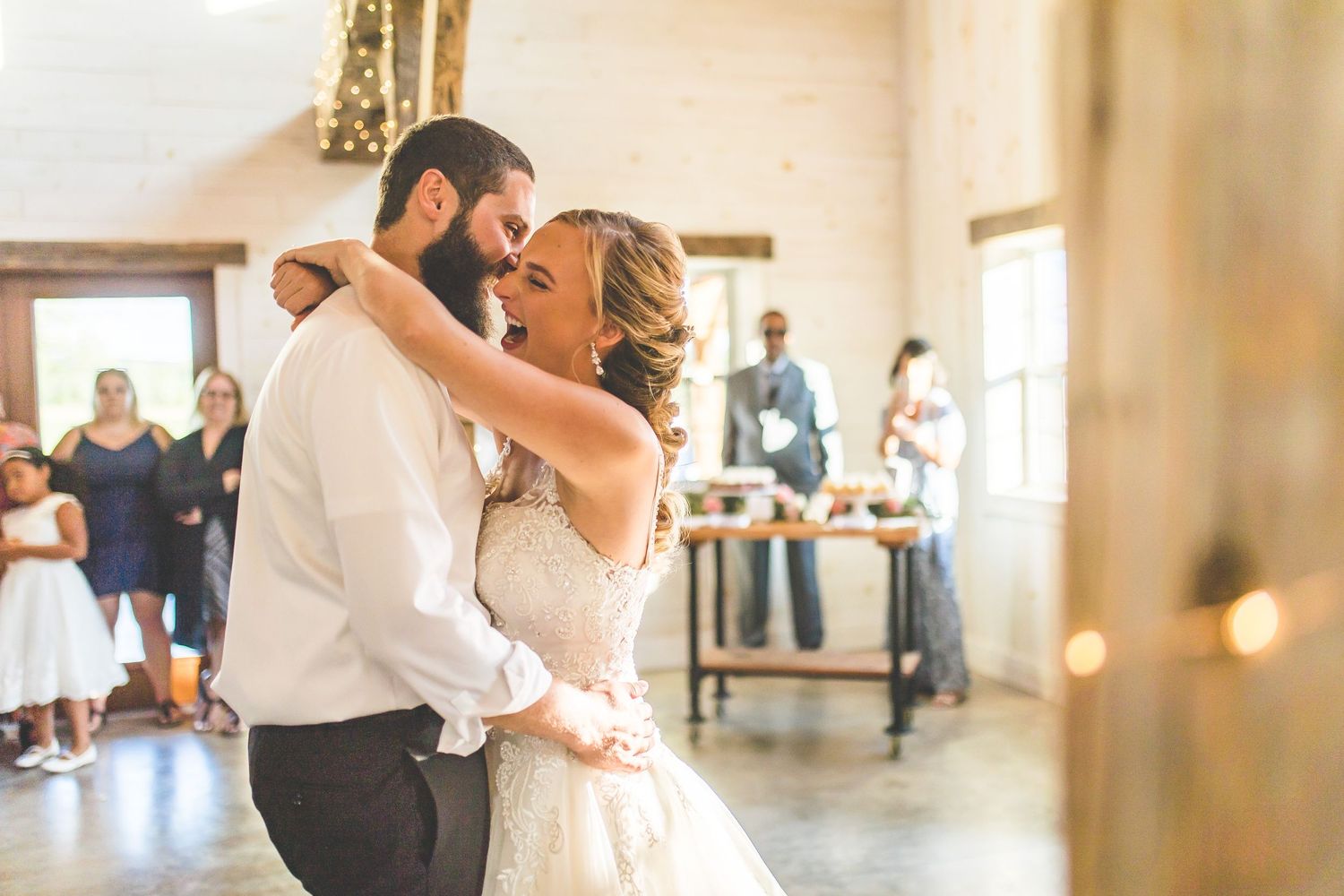 A romantic dance moment captured between newlyweds in a light-filled rustic venue.