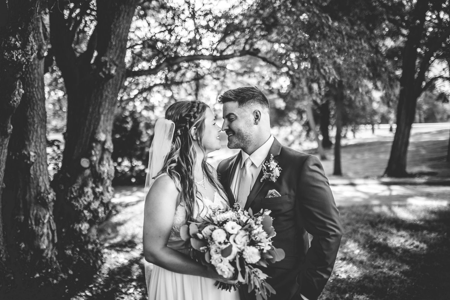 Romantic wedding portraits captured under trees in natural outdoor lighting.