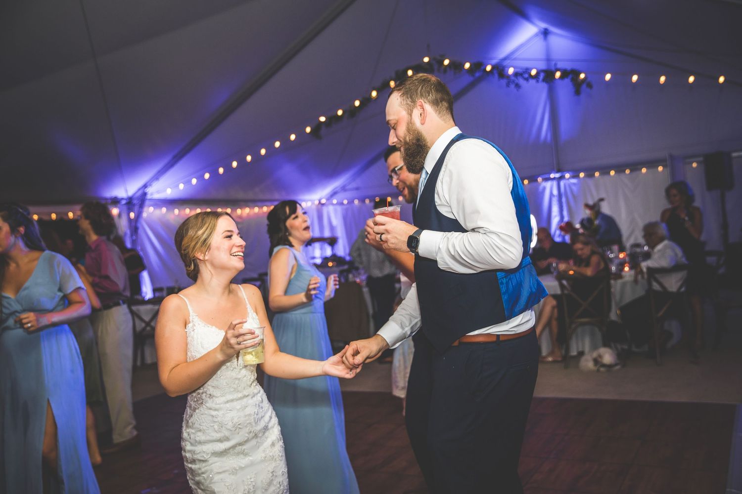 Wedding reception dance party with string lights and blue uplighting creating a festive atmosphere.