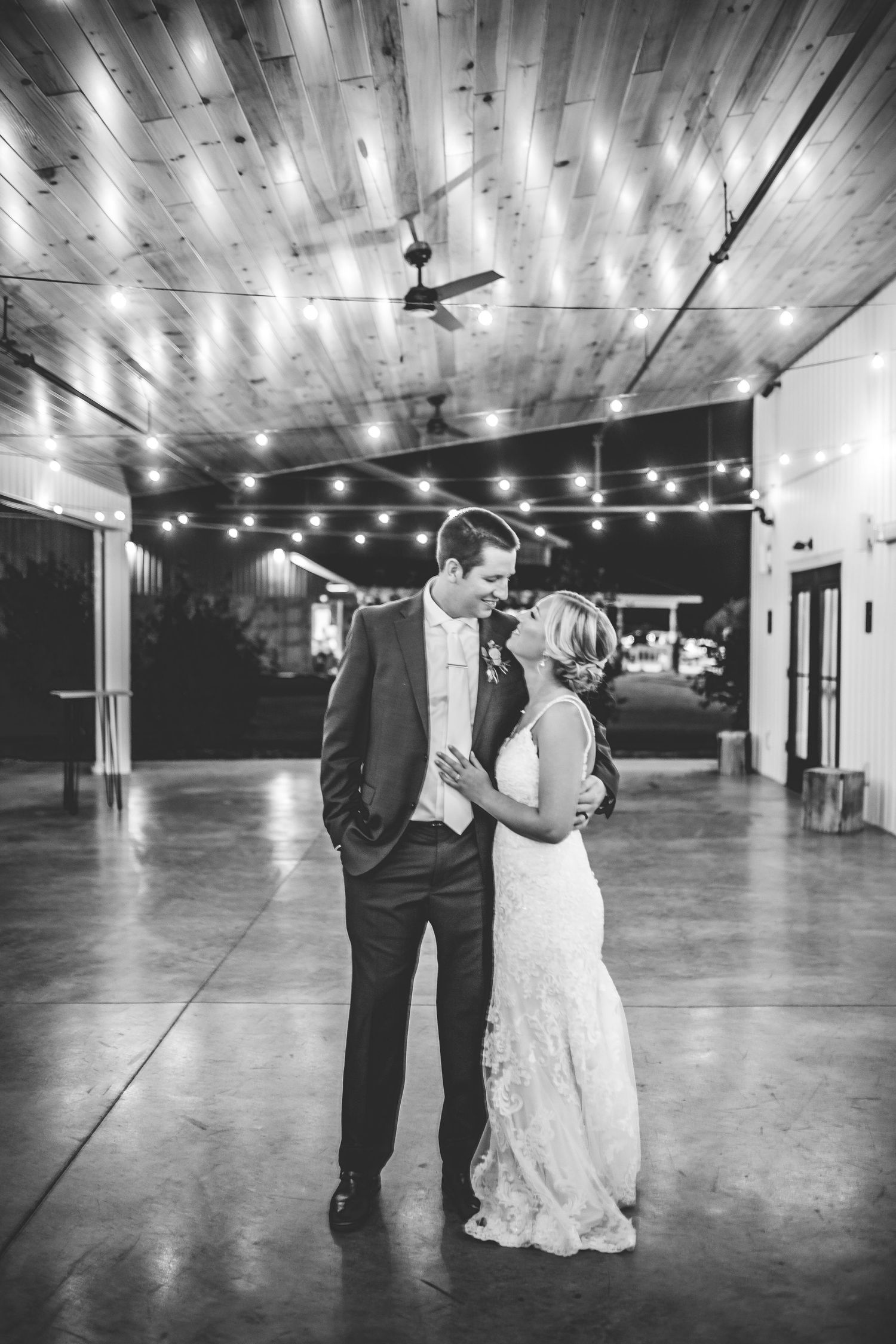 Black and white photos of couples dancing in an empty venue with string lights overhead.