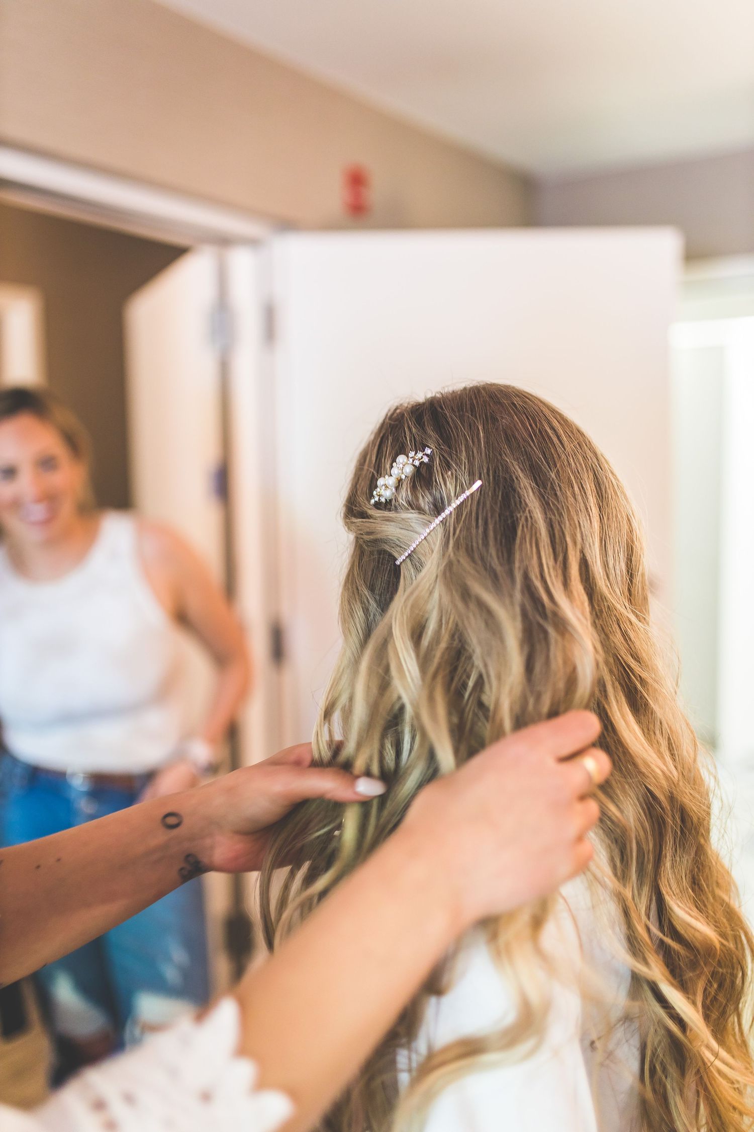 Hairstylist working on wedding day hairstyle with soft natural lighting.