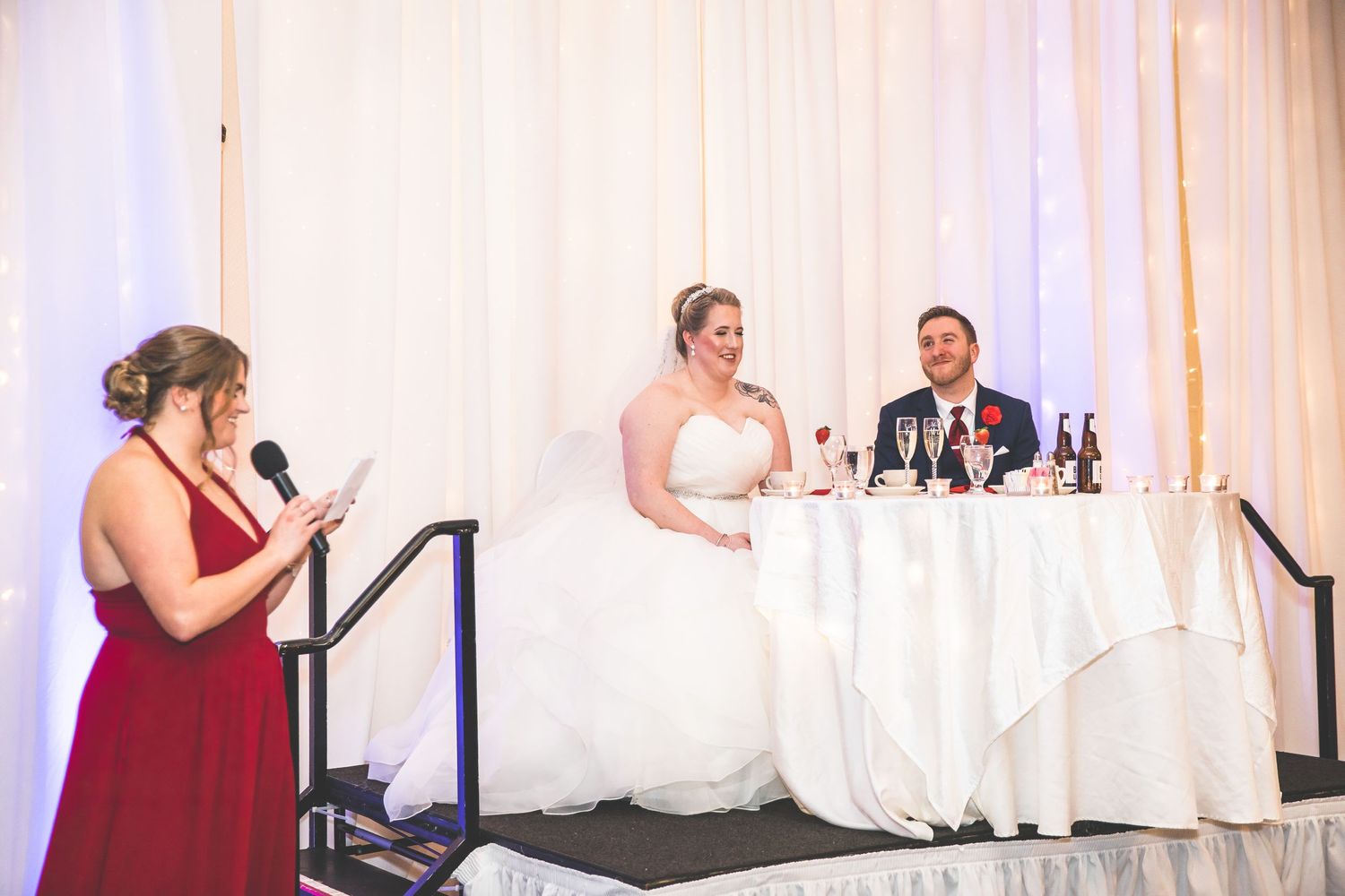Wedding reception venue decorated with elegant white drapes and lighting for formal dinner seating.