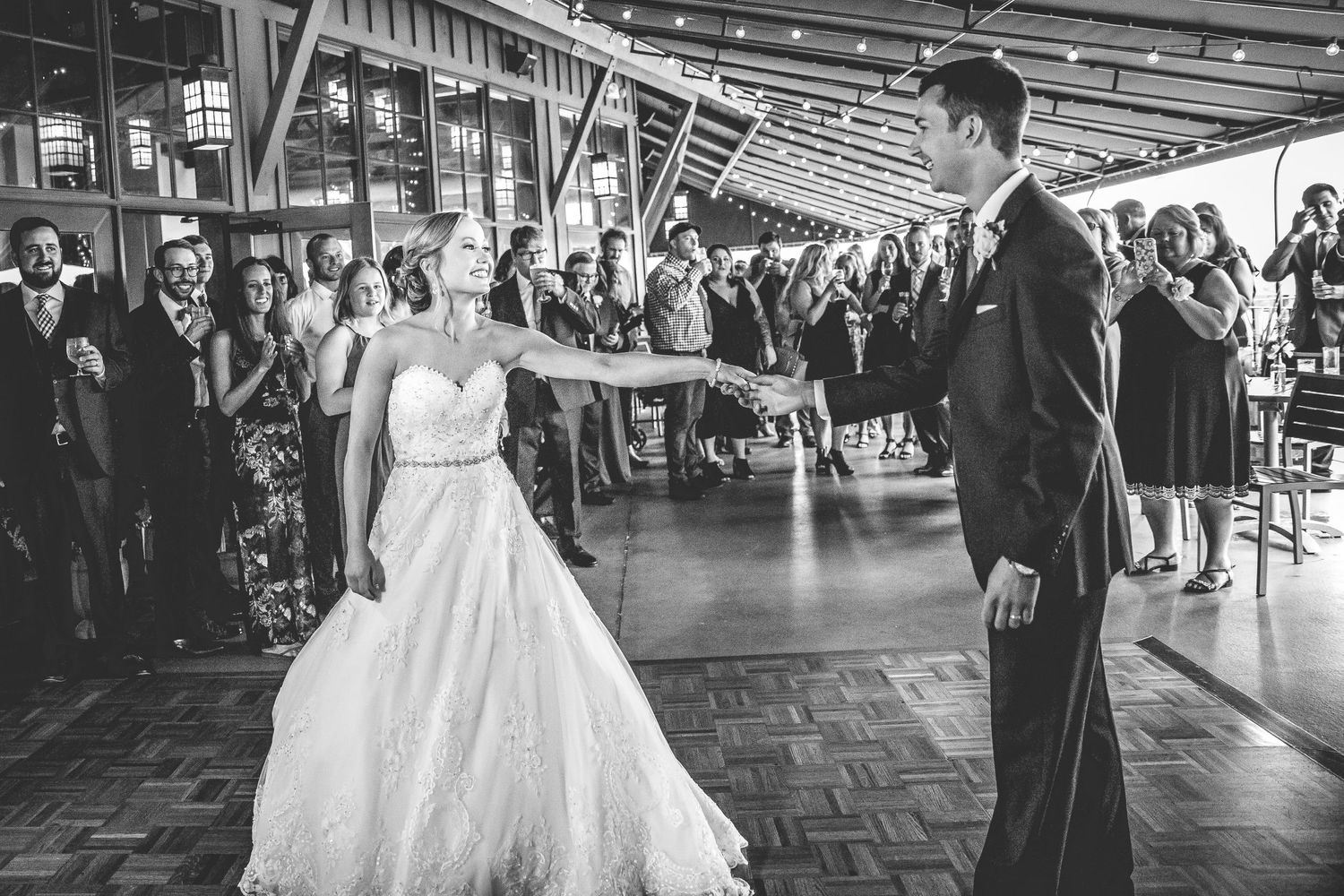 Black and white photo of a couple's first dance in an industrial-style reception venue.