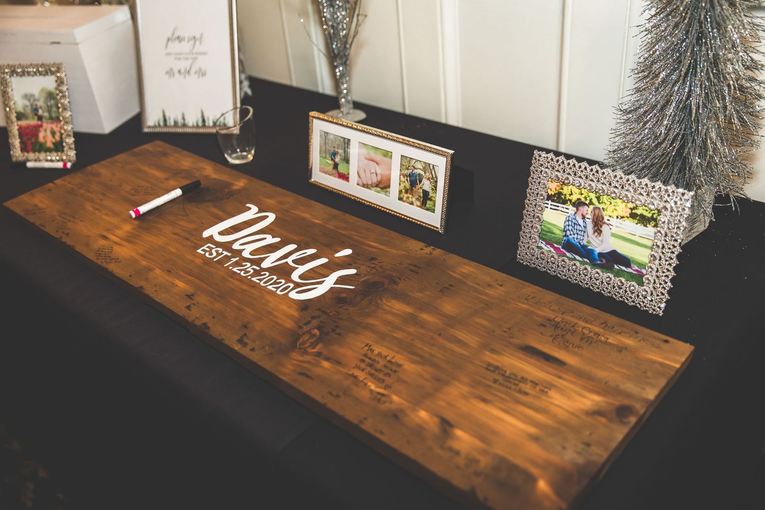 Rustic wooden table display with picture frames and decorative elements at a wedding reception.