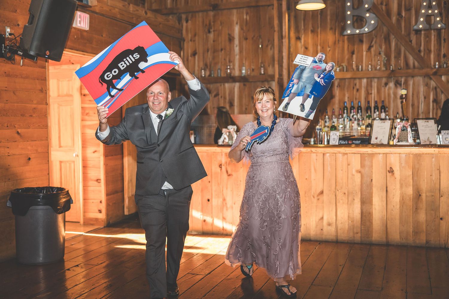 Wedding reception venue with rustic wooden walls decorated with string lights and flags.
