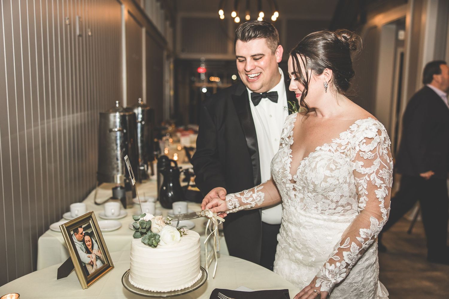 Couple cuts their elegant white wedding cake together at the reception.