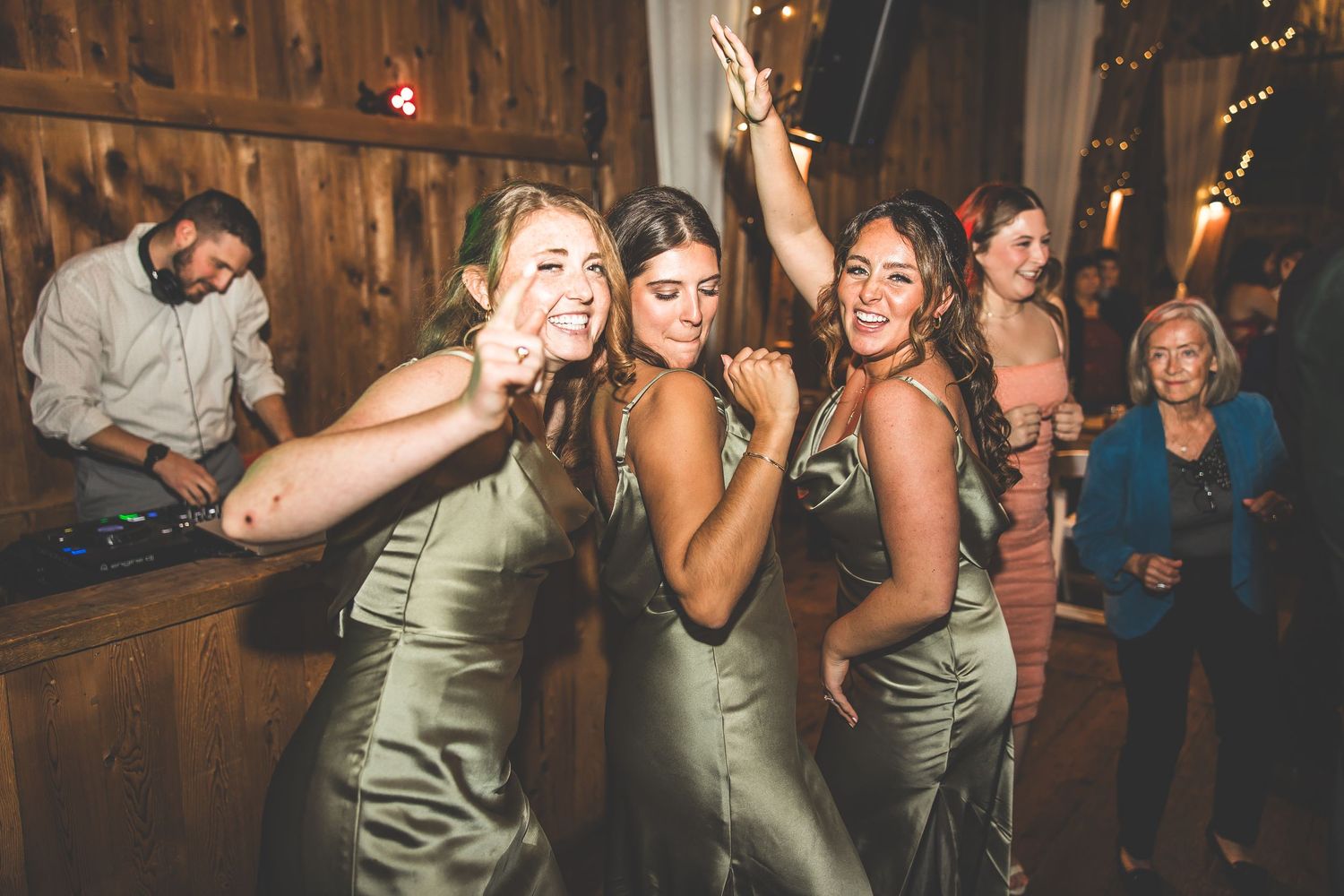 Party guests dancing in a rustic wooden venue with warm lighting and festive atmosphere.