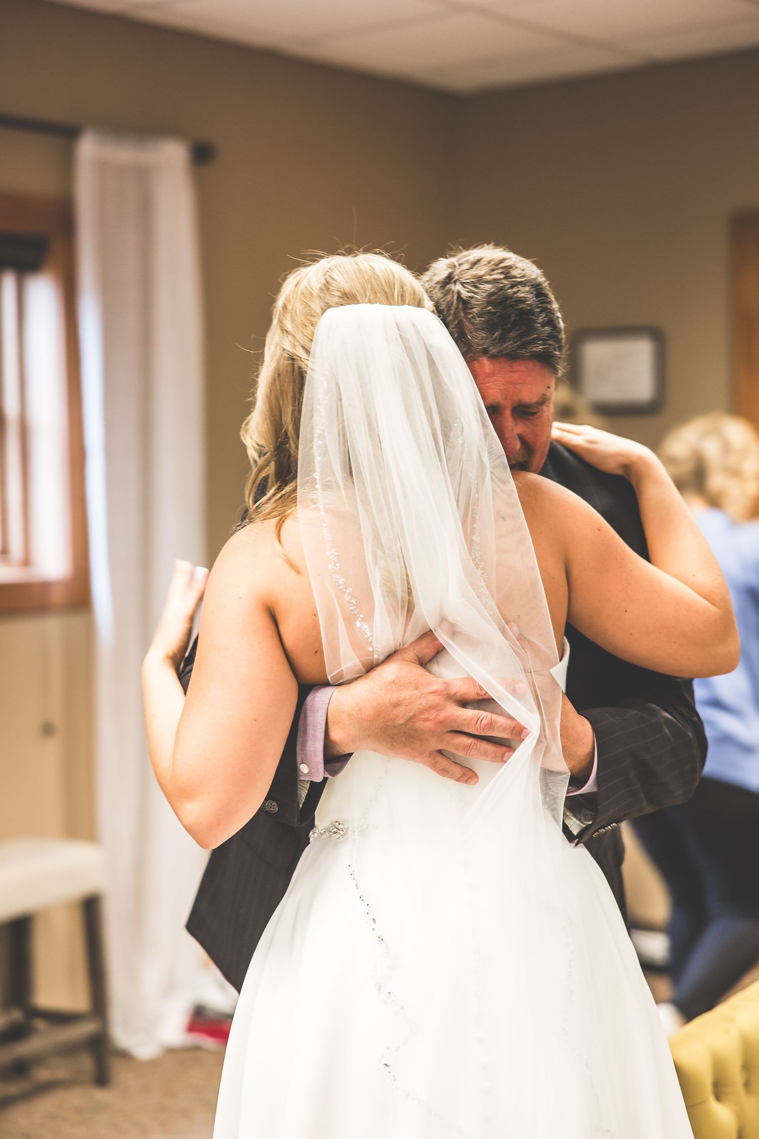 An emotional moment captured during wedding preparations with a flowing white veil.