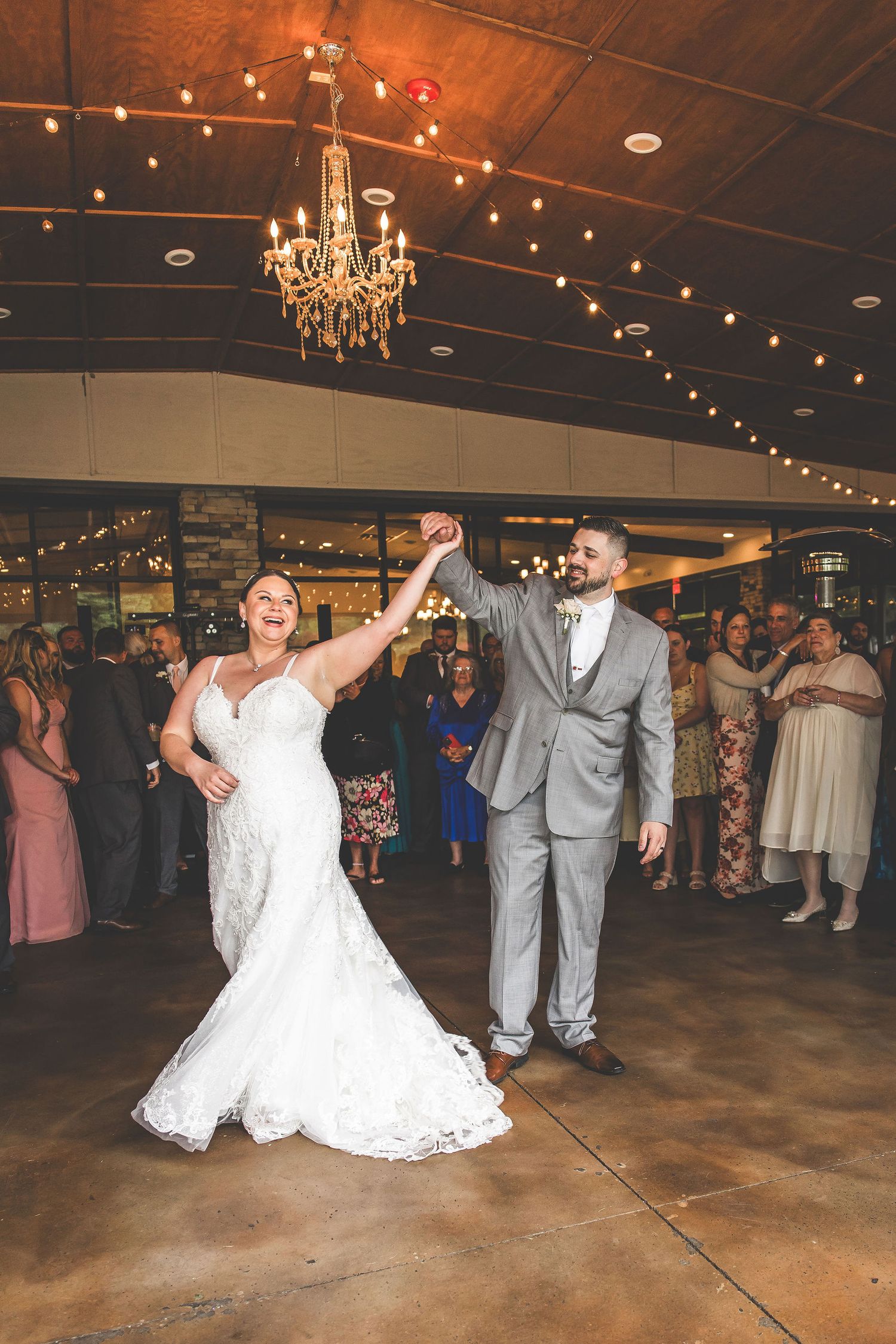 Wedding couple performs choreographed dance moves surrounded by guests in a reception hall.