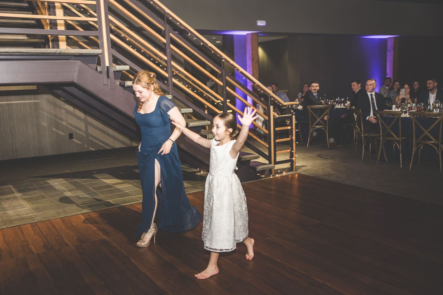 Dance floor at wedding reception with wooden stairs and purple accent lighting.