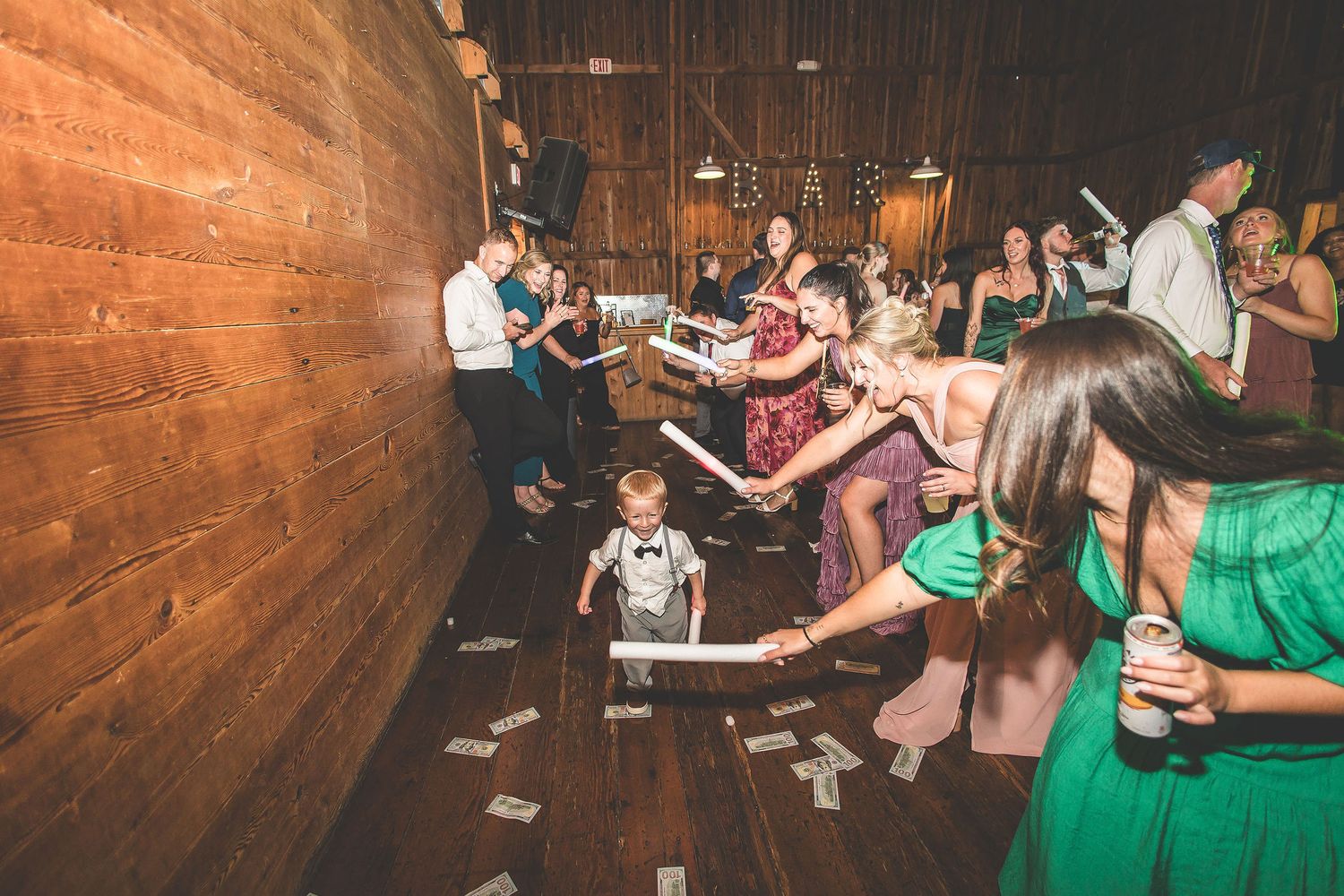 Wedding reception dance floor in a rustic wooden barn with warm ambient lighting.