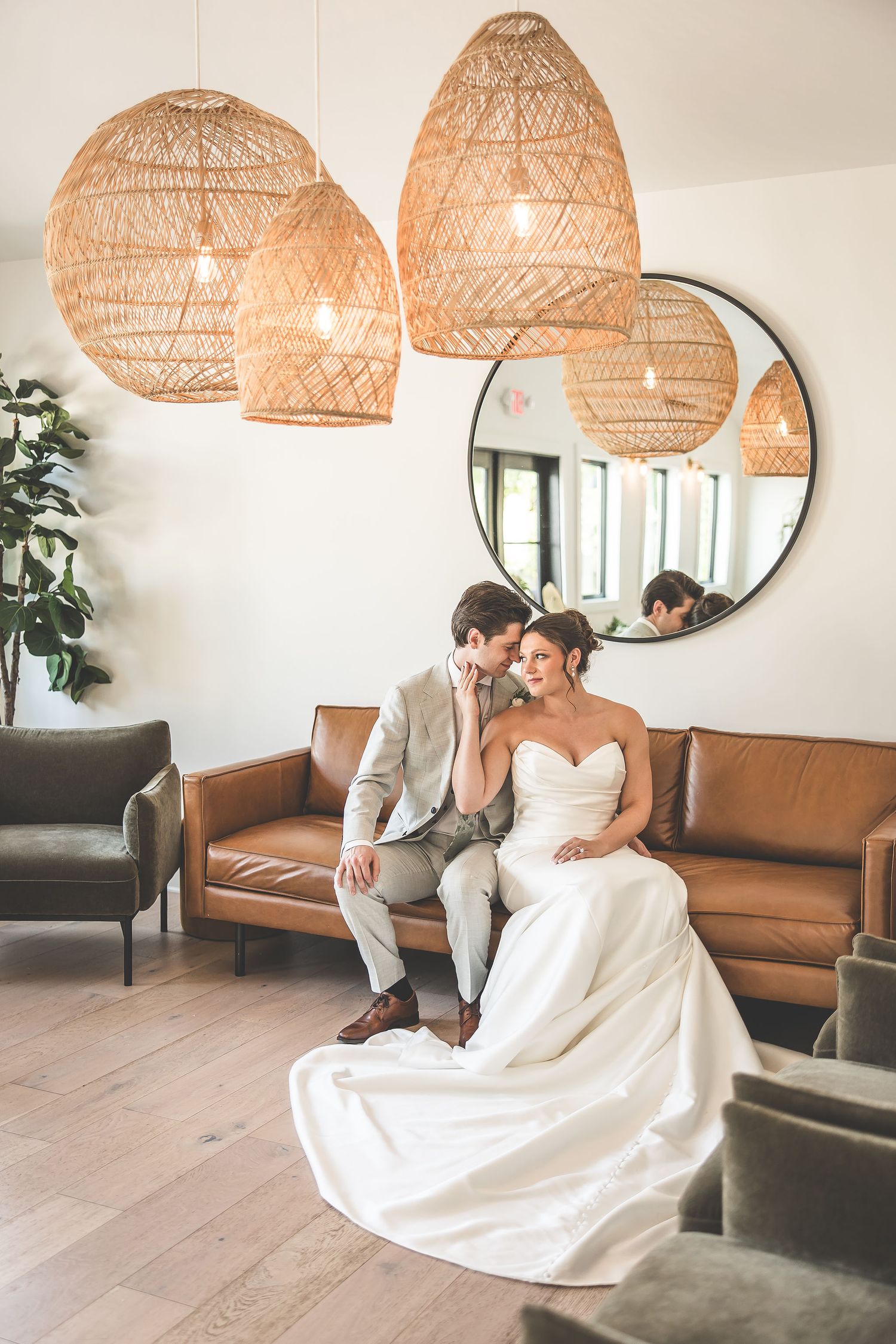 Romantic wedding photos taken in a minimalist room with rattan pendant lamps and leather furniture.