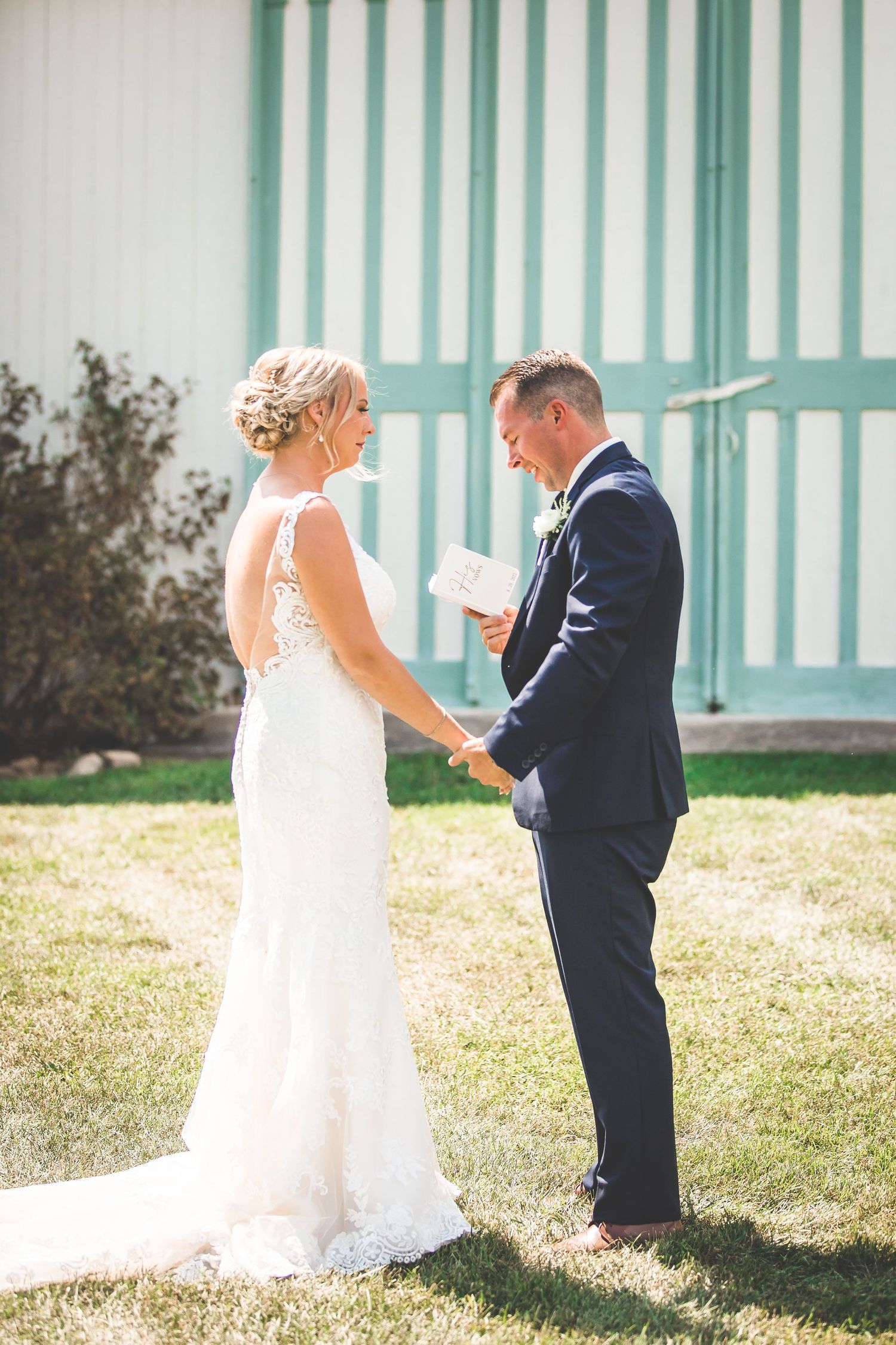 A tender moment between newlyweds during their first look against a striped turquoise wall.