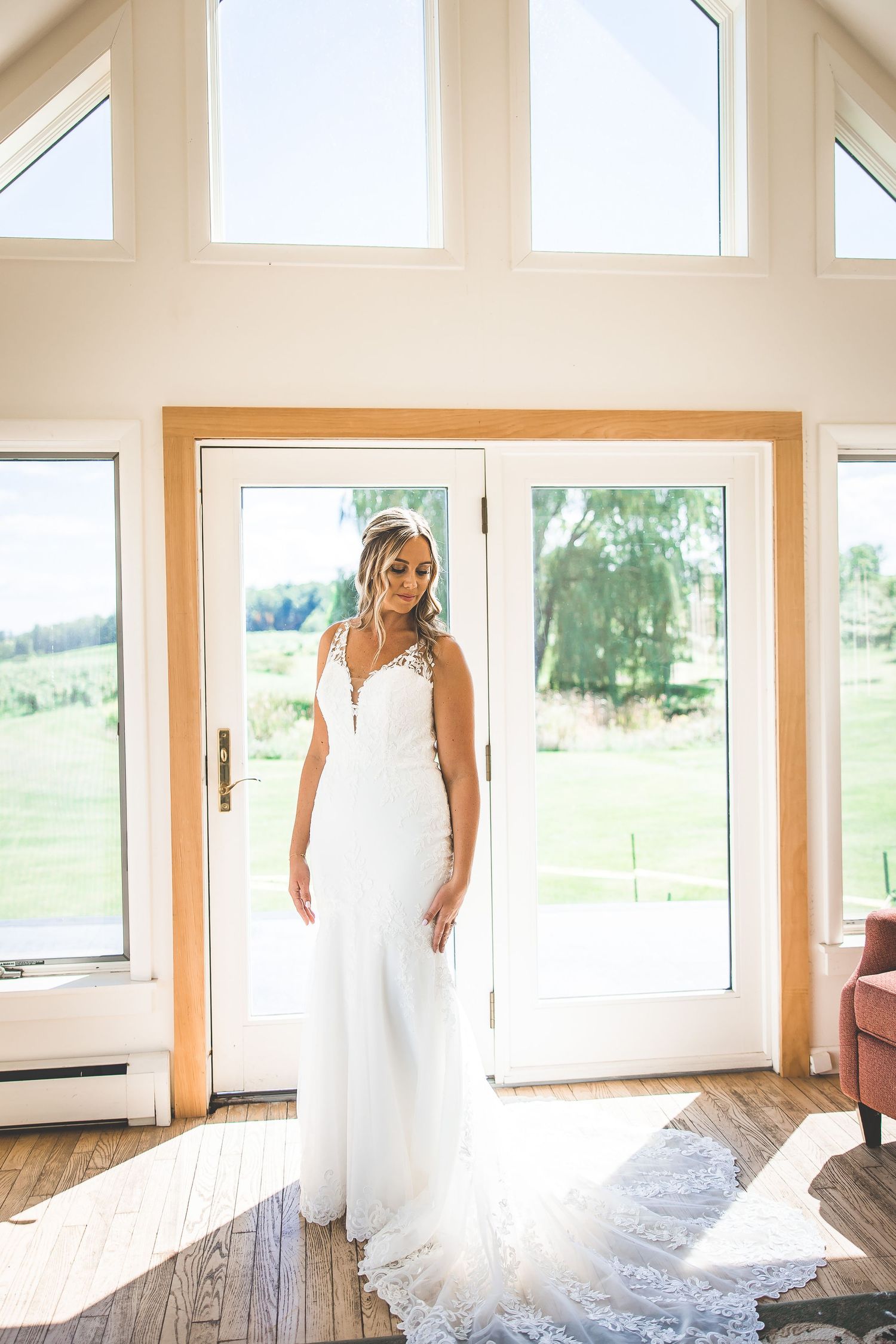 Bridal gown displayed in natural light against large windows with countryside view.