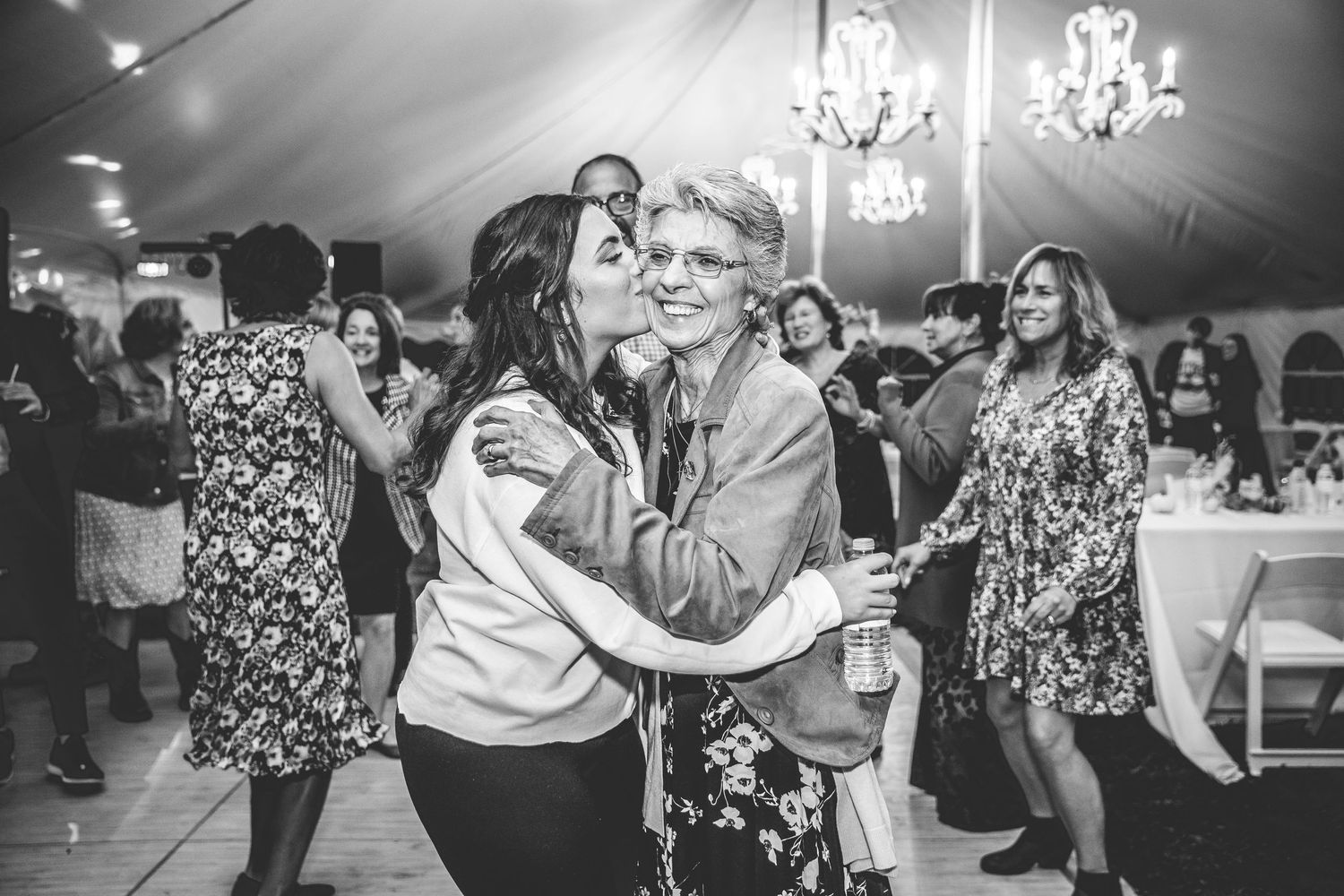 Wedding reception dance party with guests enjoying themselves under chandelier lighting.