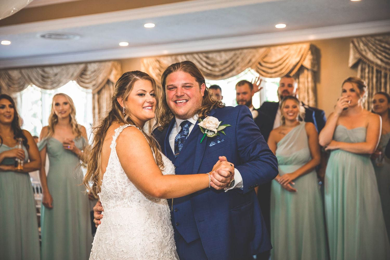 Wedding party in blue suits and mint green dresses celebrates during reception.