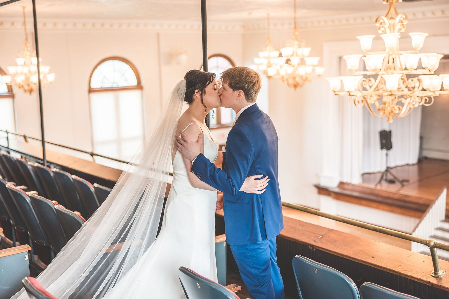 Two people embrace during their first look in an elegant wedding venue with chandeliers.