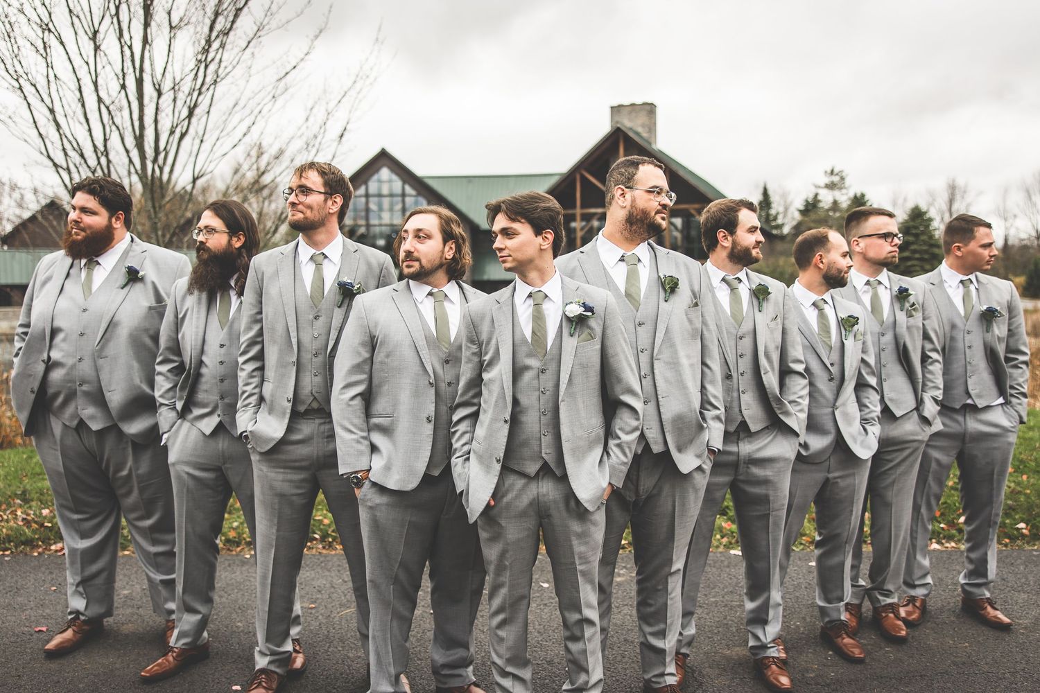 Wedding party groomsmen in gray suits pose creatively for outdoor group shots.