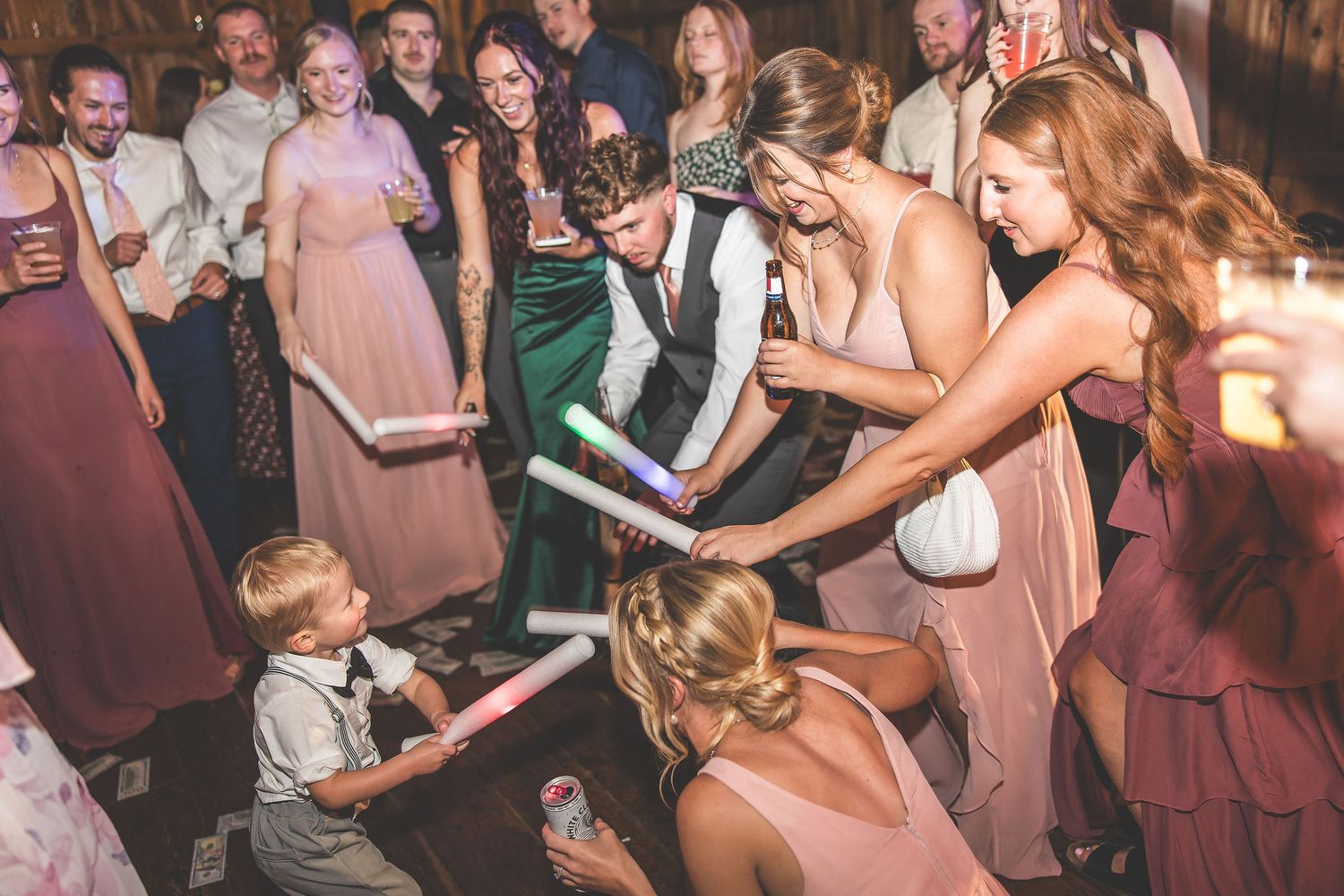 Wedding guests dancing with young child at reception with pink and green formal attire.