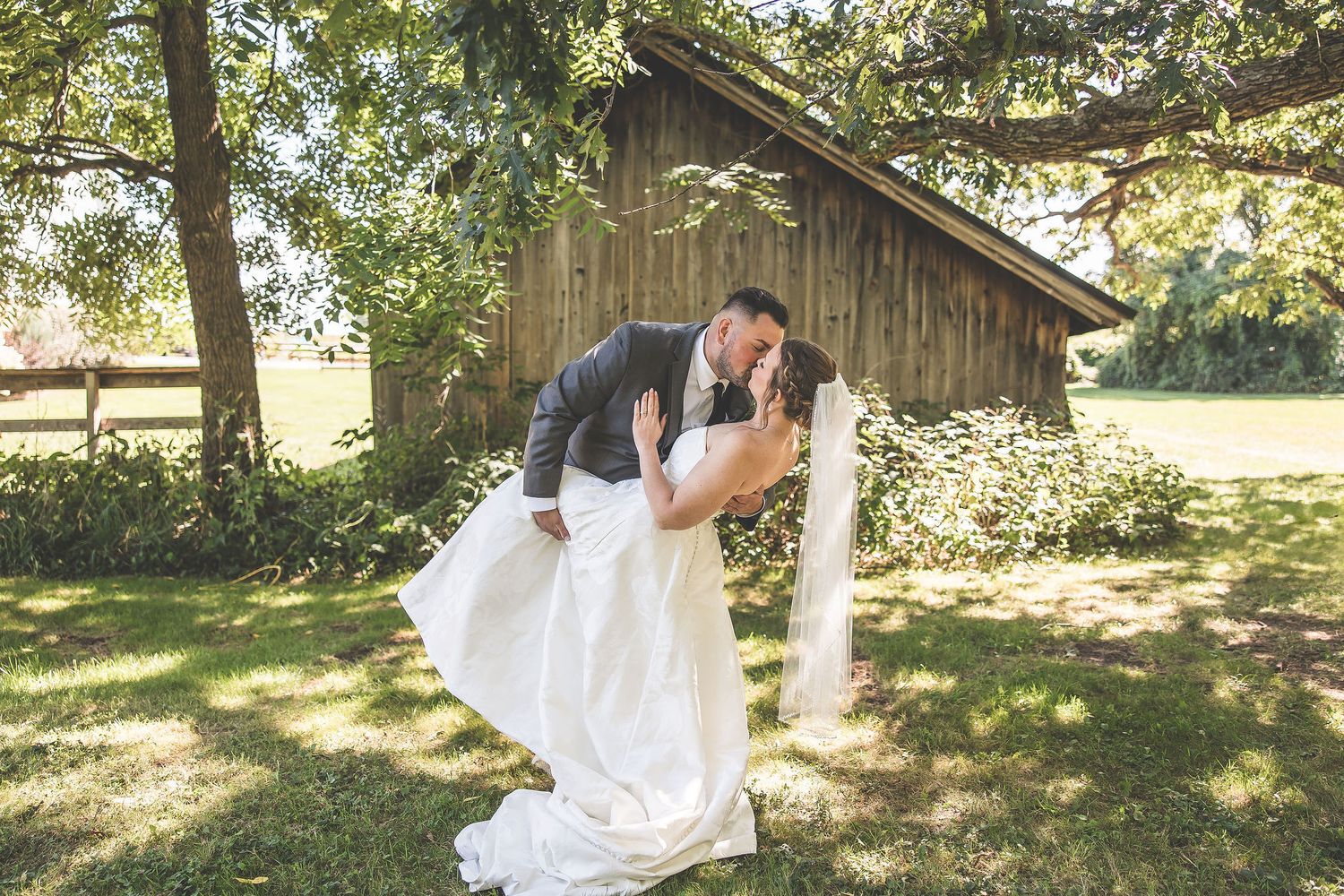 Wedding couple poses together in multiple shots against a rustic wooden barn backdrop.