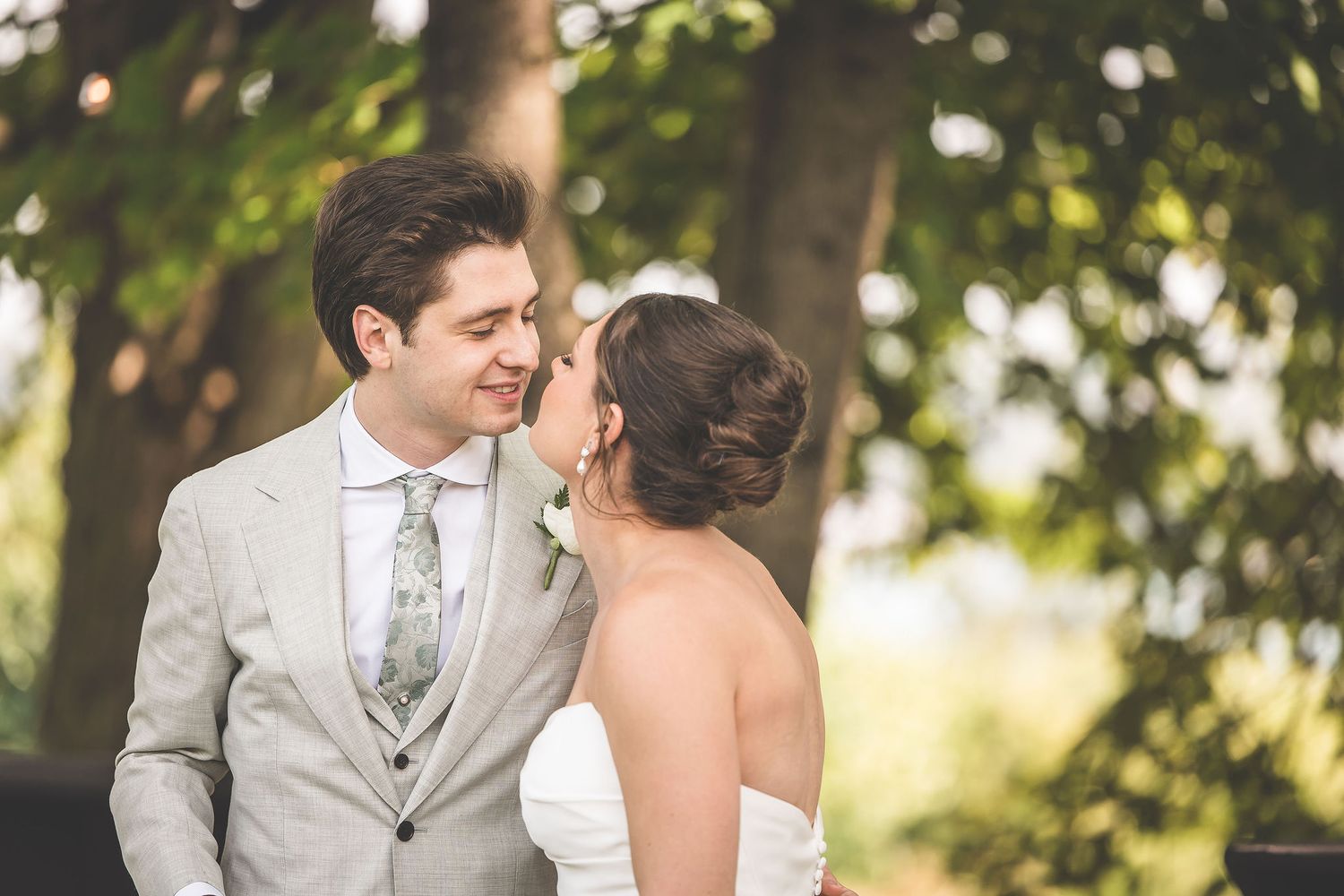 Intimate wedding portraits captured in a sunlit garden setting with natural foliage.