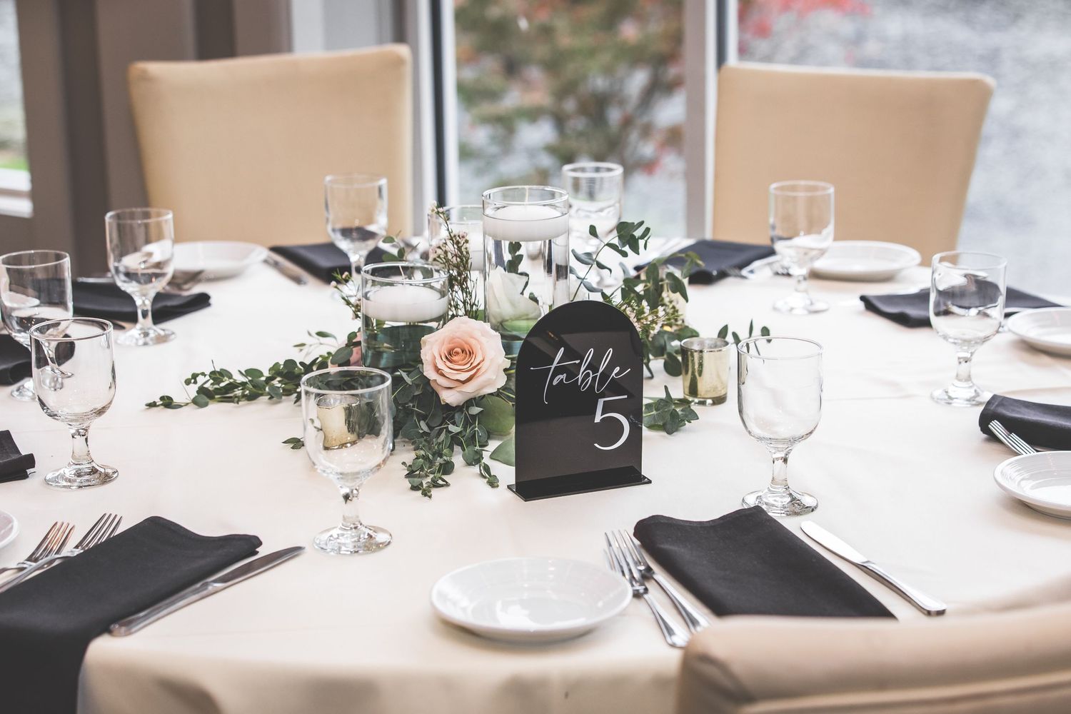 Elegant wedding reception table settings with white linens and black accents.