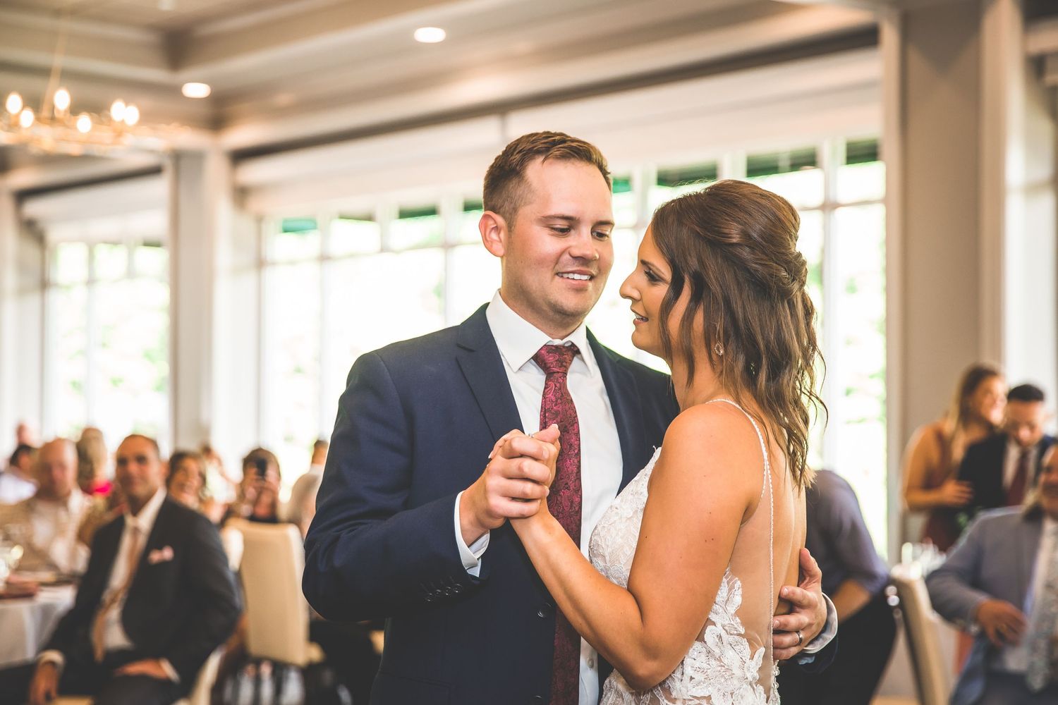 Wedding reception guests mingling in an elegant venue with natural lighting.