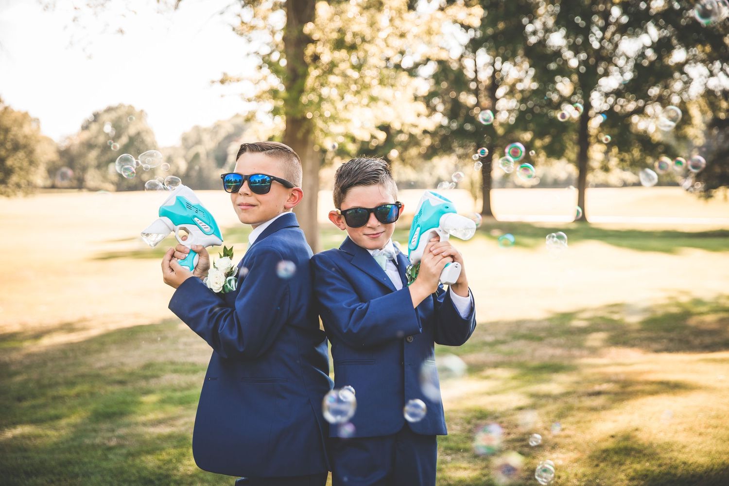 Wedding party members in navy suits posing with sunglasses outdoors.