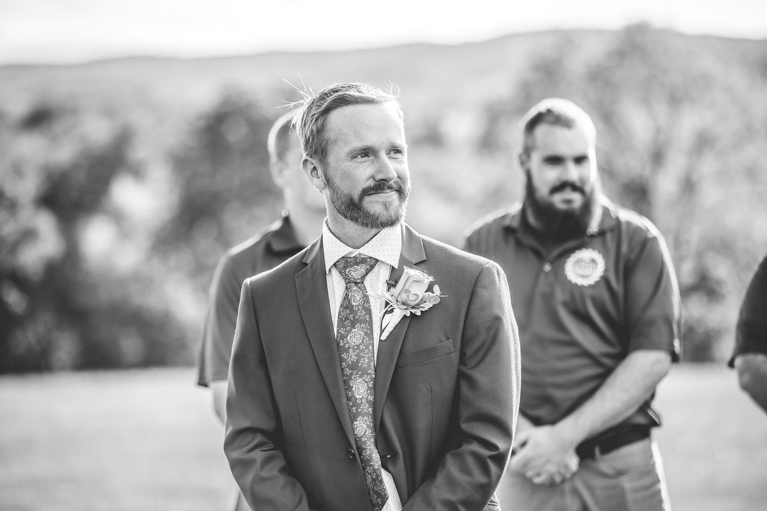 Black and white portrait of person in formal attire at outdoor wedding.