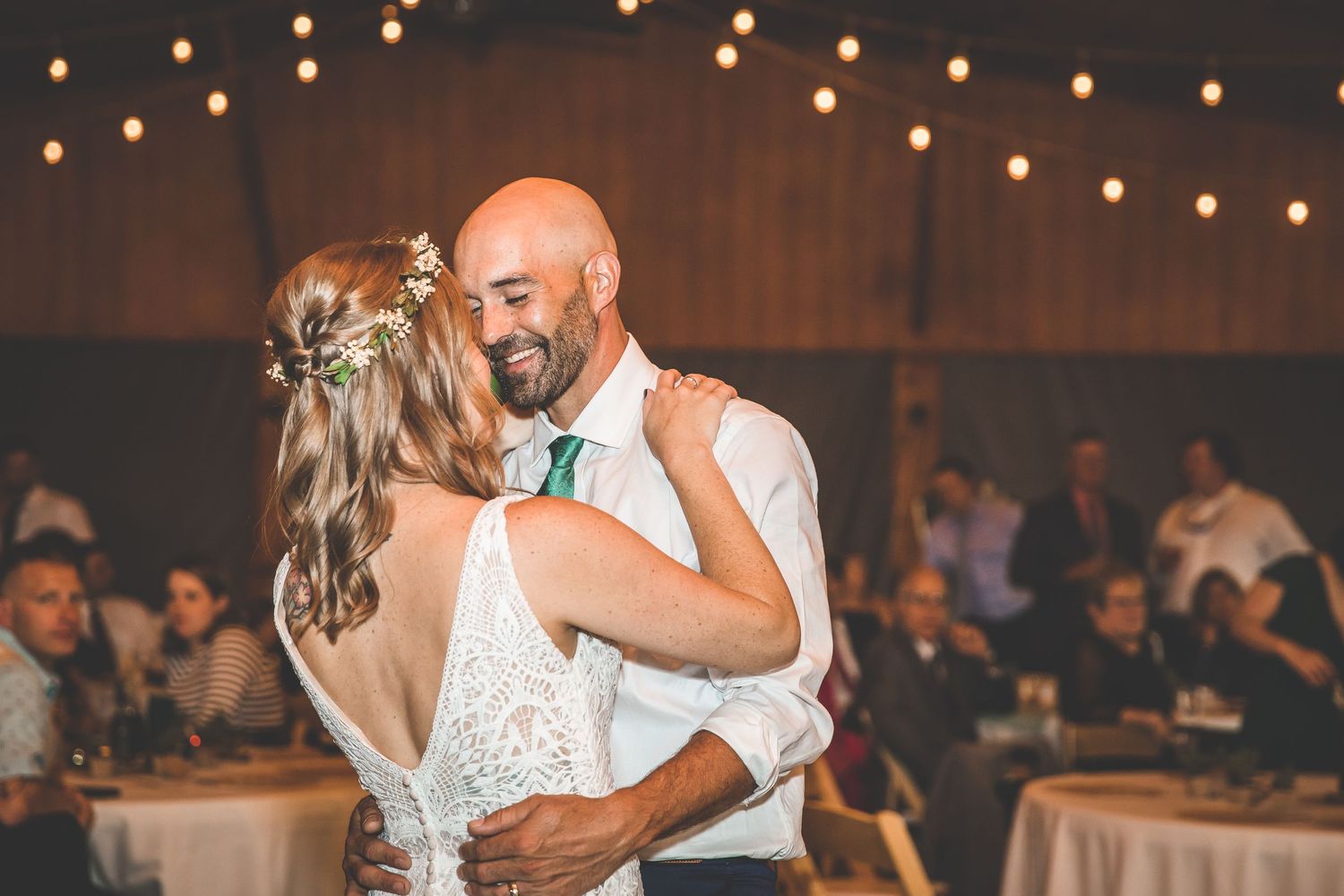 Wedding reception dance floor illuminated by warm string lights overhead.