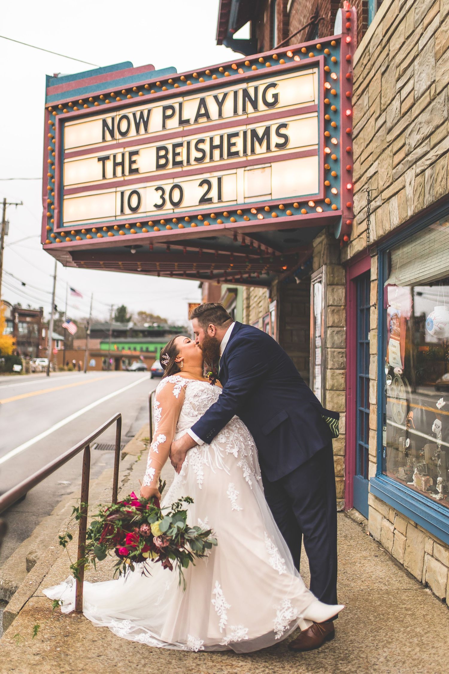 Wedding couple poses romantically under vintage theater marquee on their special day.
