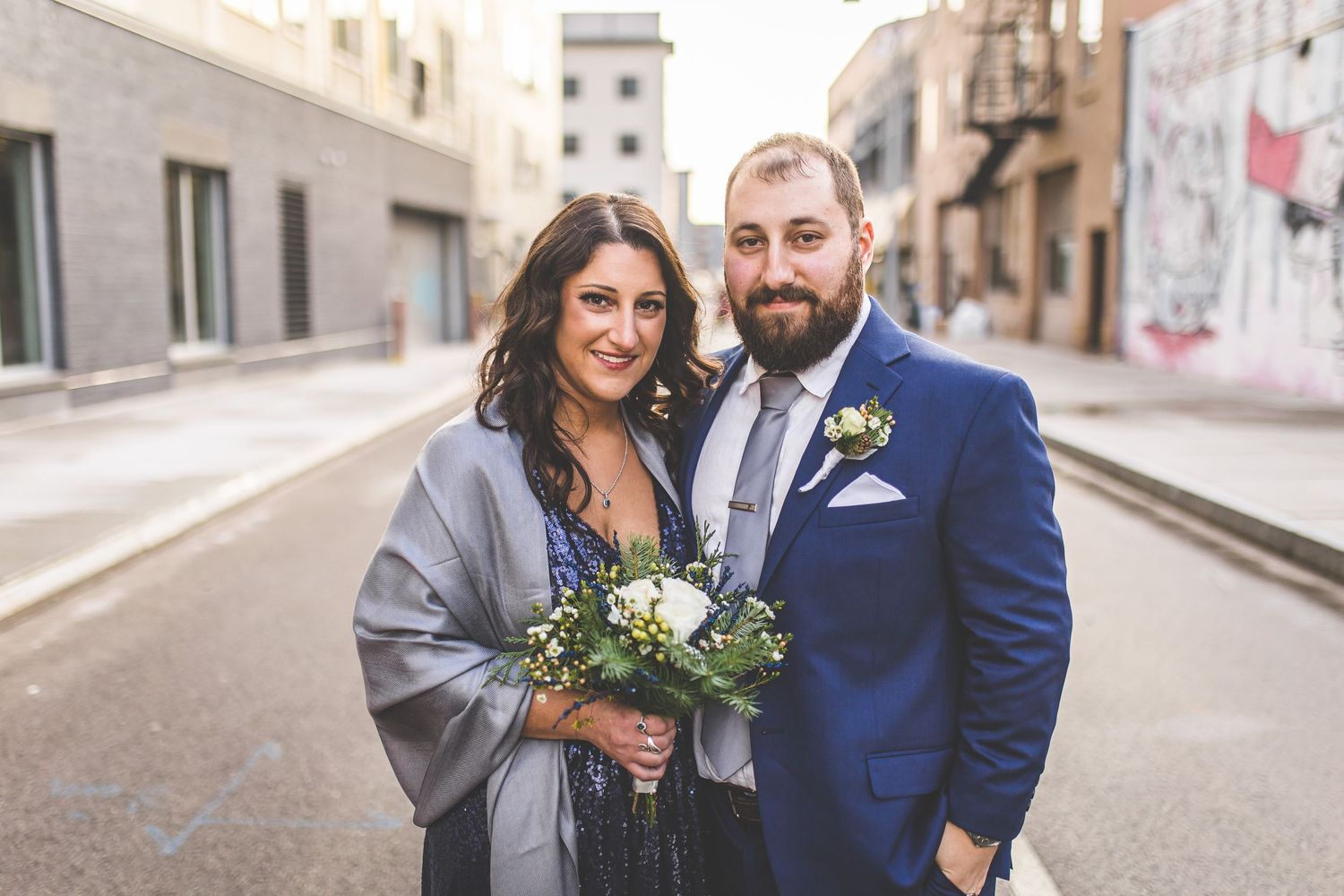 Wedding group gathers for candid portraits against urban backdrop.