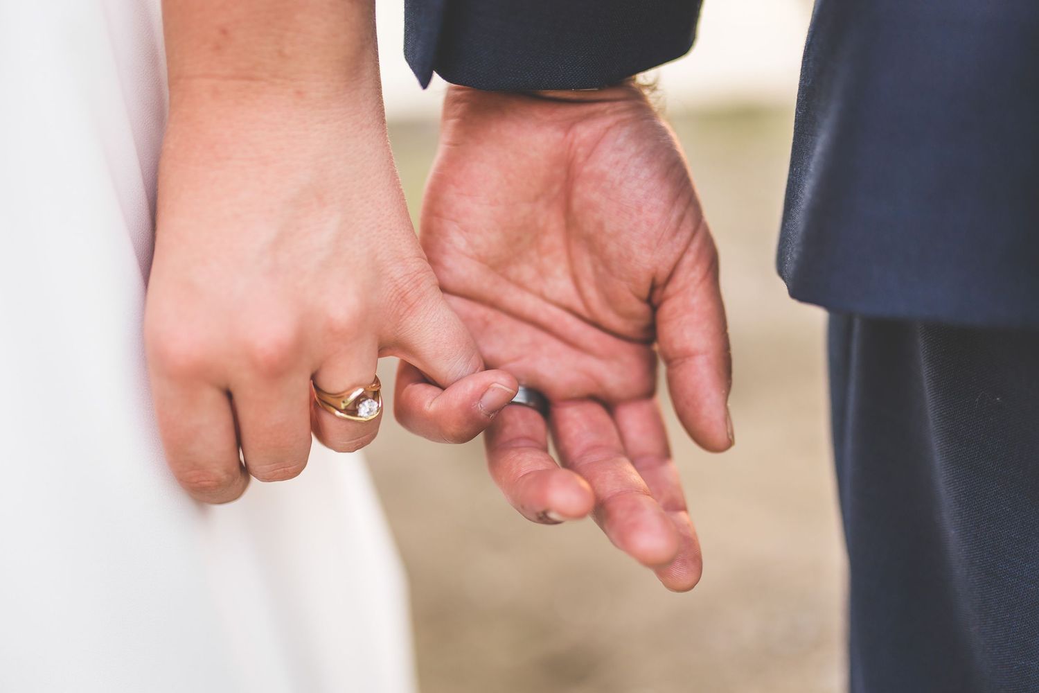 Close-up of hands showing wedding rings against formal attire.