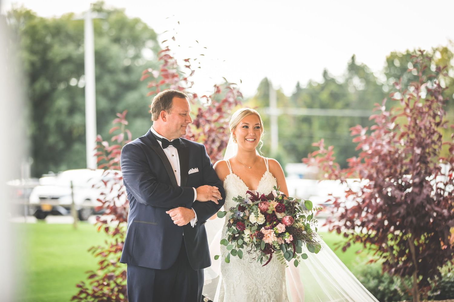 Romantic outdoor wedding scene with lush greenery and floral arrangements.
