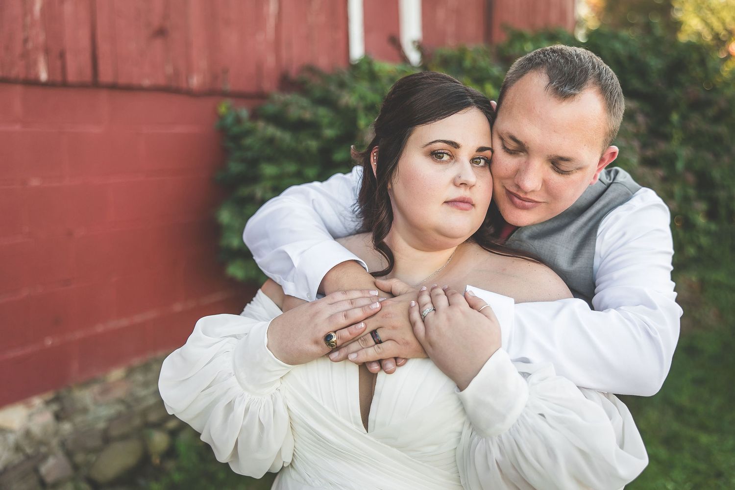 Couple sharing intimate moments against a rustic red barn backdrop during a wedding photoshoot.
