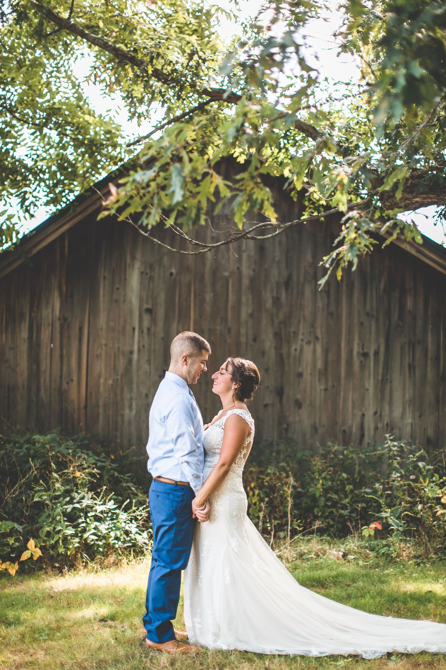 Wedding couple shares intimate moments in a garden setting with wooden fence backdrop.