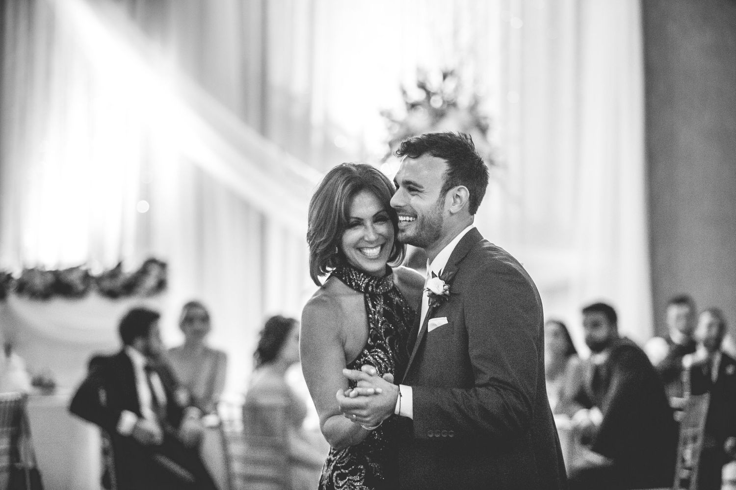 A couple shares a joyful dance moment at an elegant indoor wedding reception.