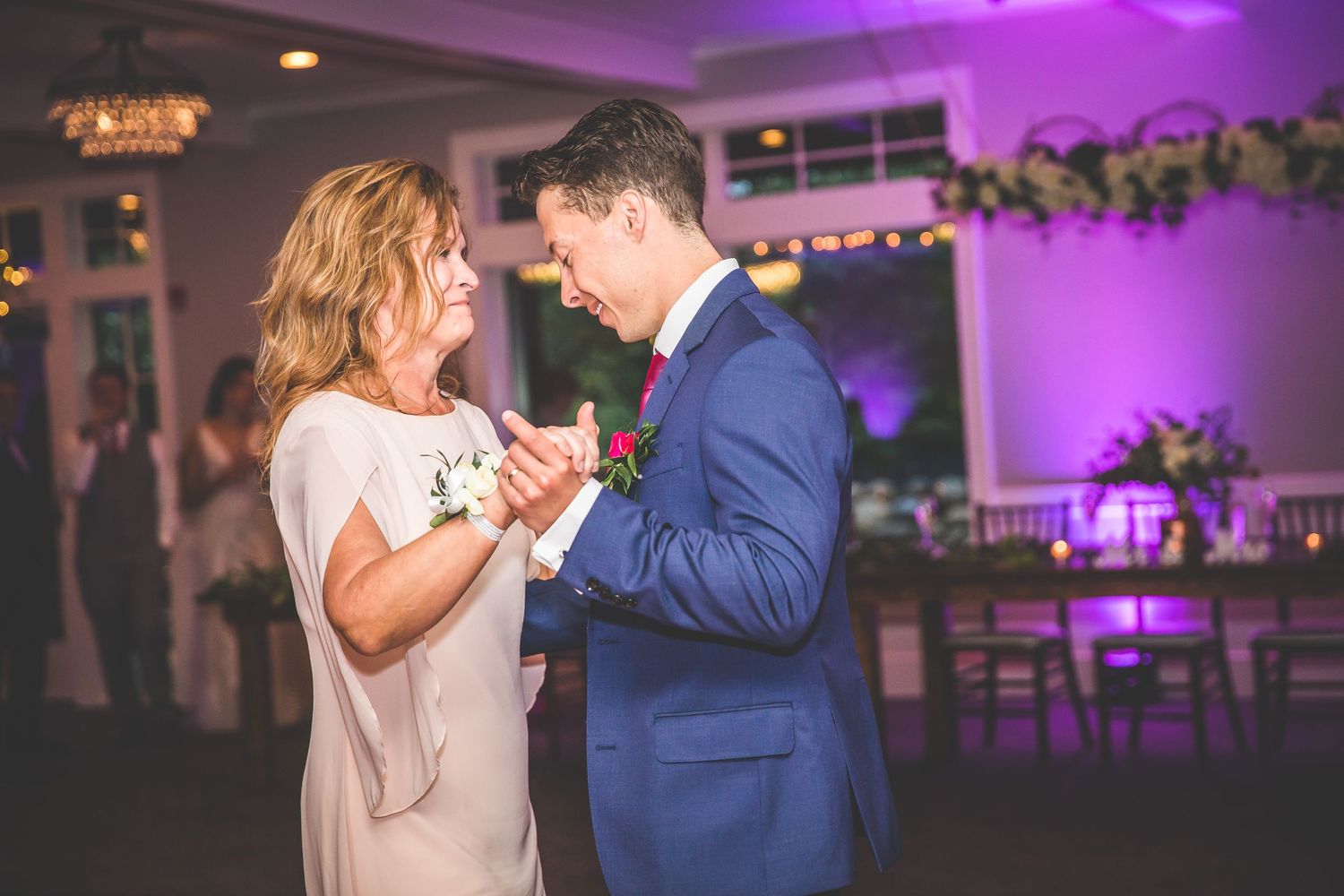 Couple shares first dance in ballroom with dramatic purple lighting effects.