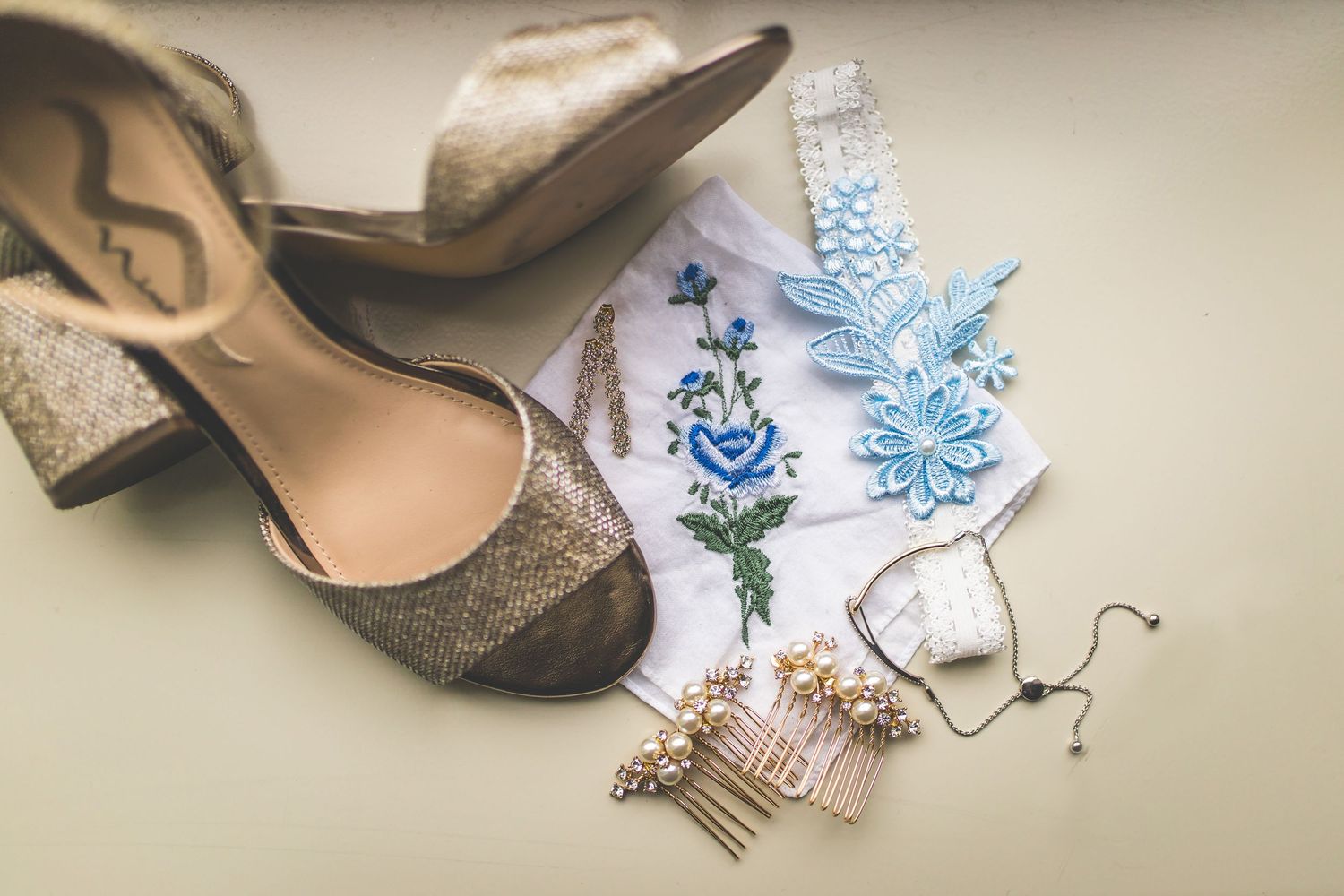 Wedding accessories including shoes, garter, and blue decorative details arranged for detail shot.