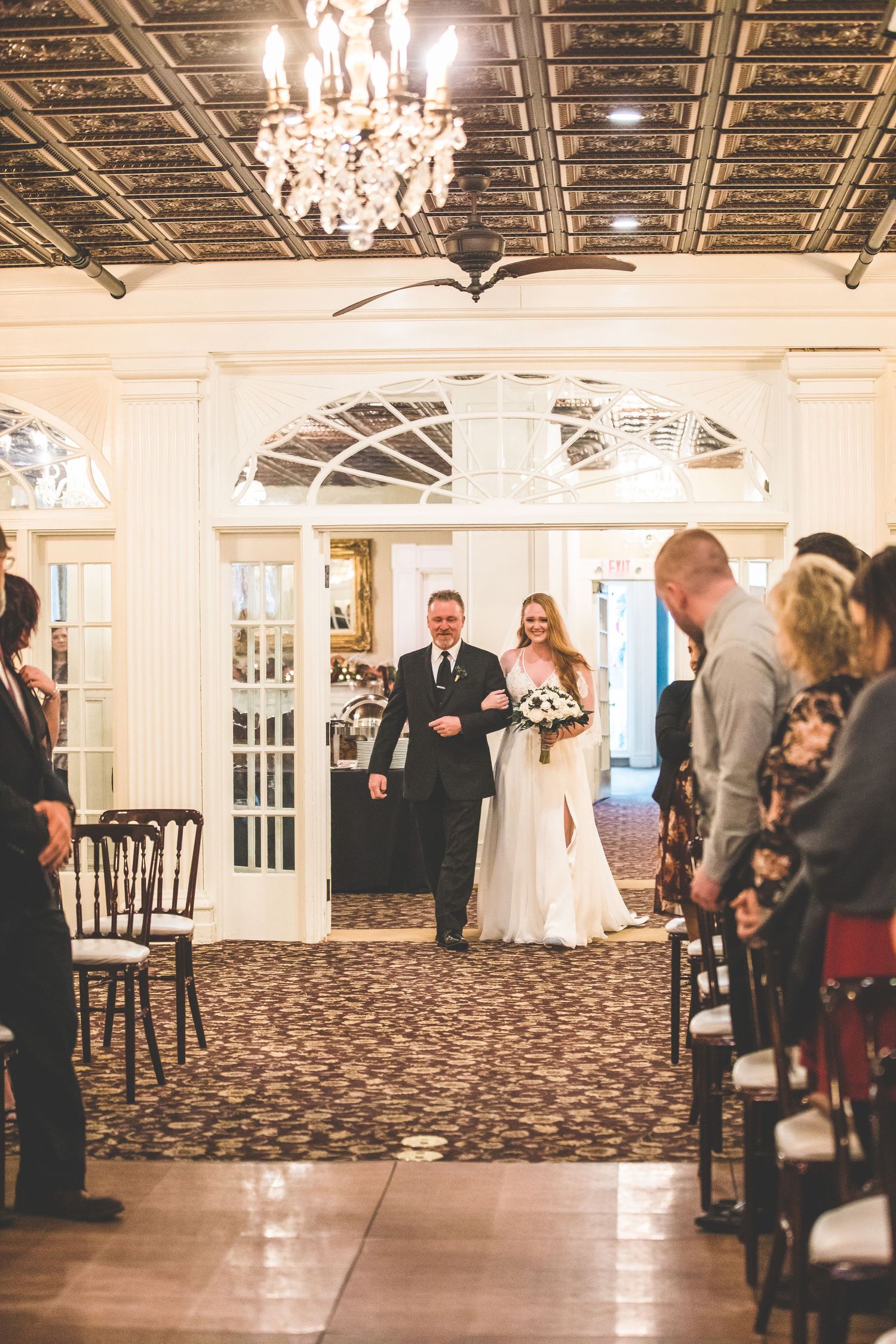 Wedding ceremony in progress in elegant ballroom with guests seated in rows.
