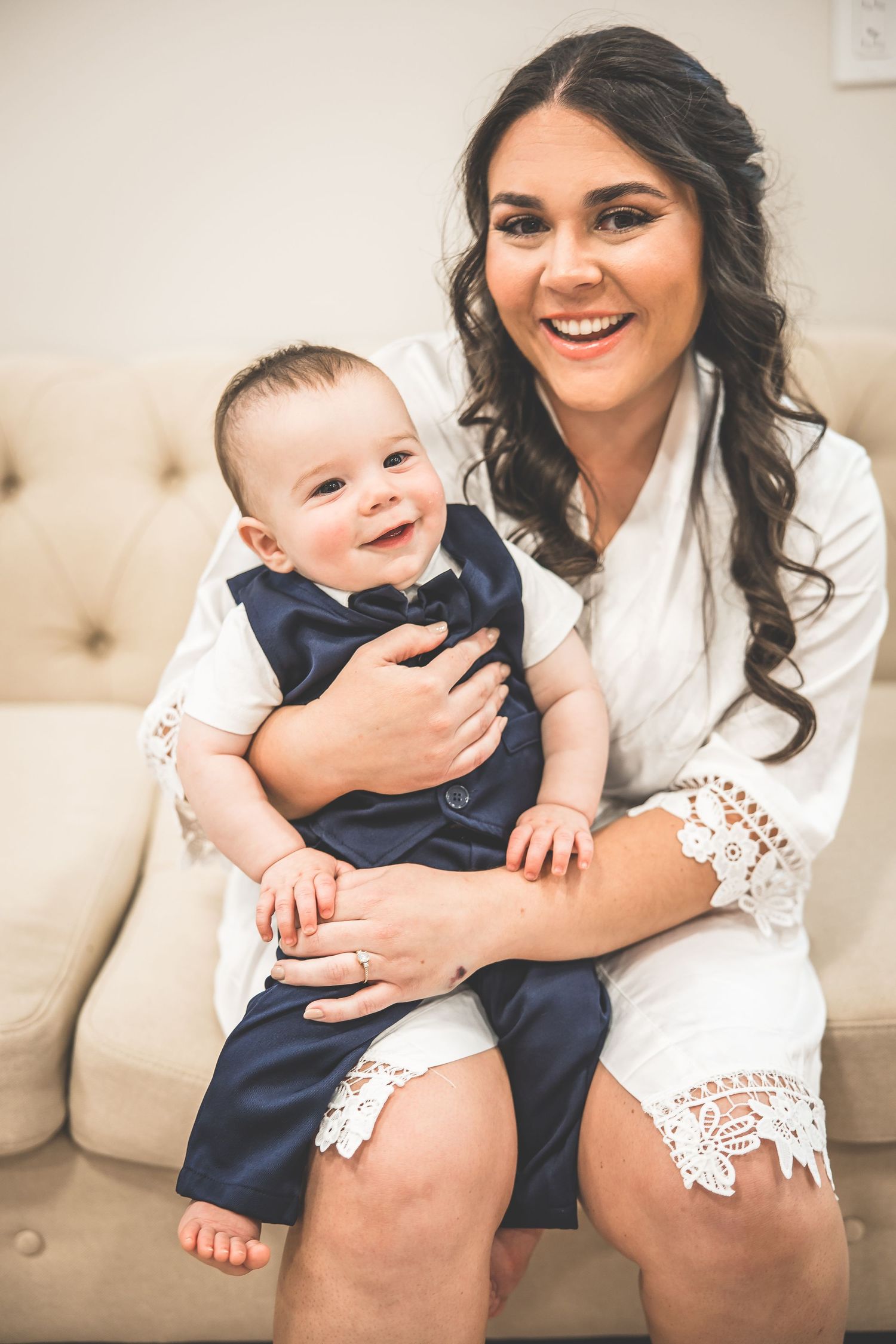 A tender moment captured on a white couch in formal attire.